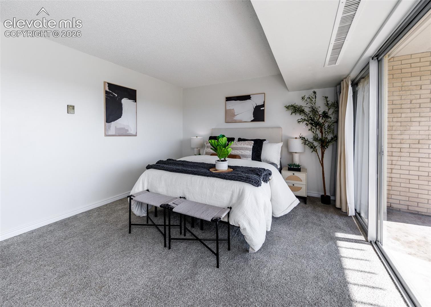 Neutral-toned carpeting, full-height sliding glass doors, and brick exterior wall