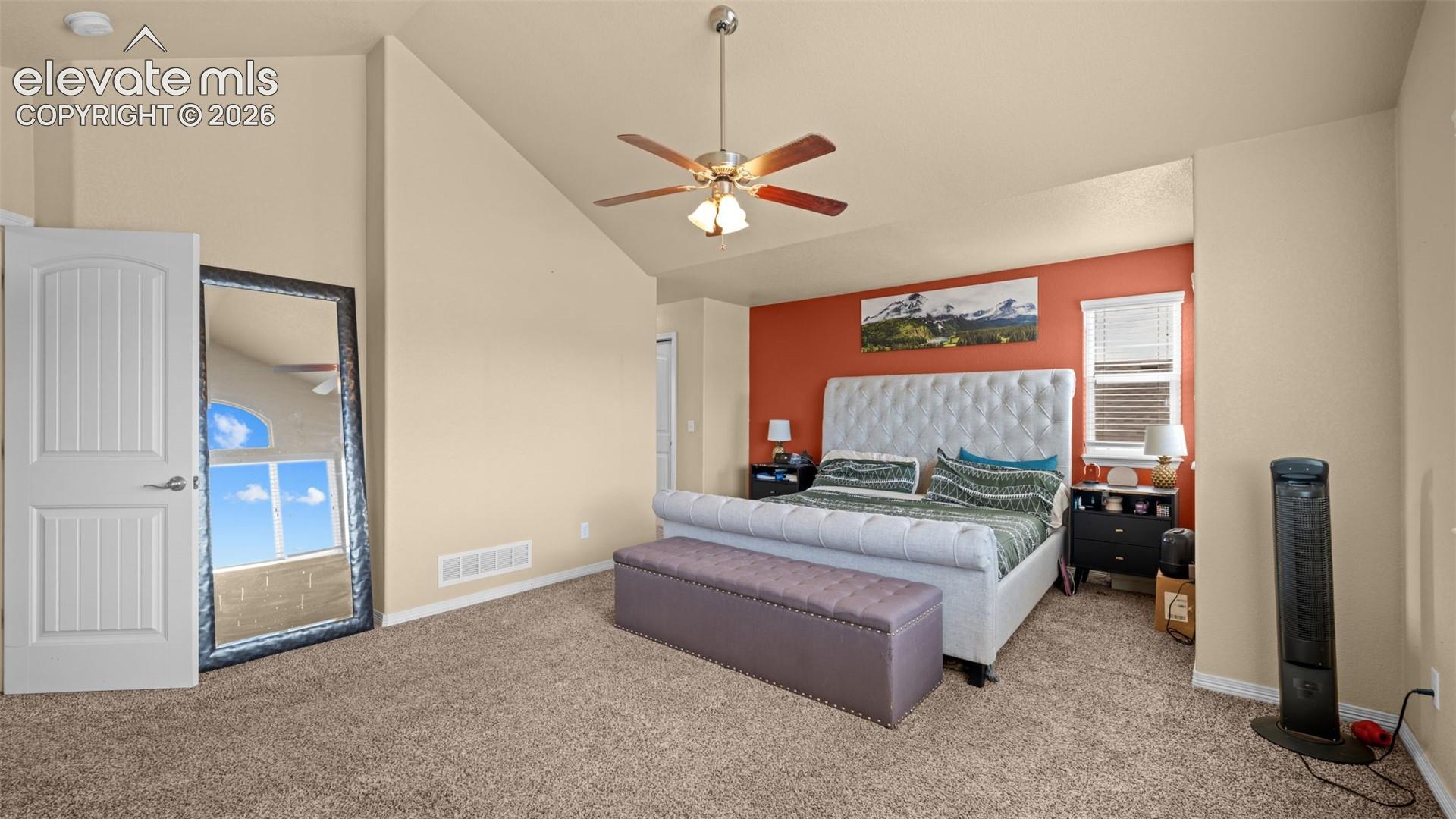 Vaulted bedroom featuring carpet flooring, ceiling fan, and a single window with blinds