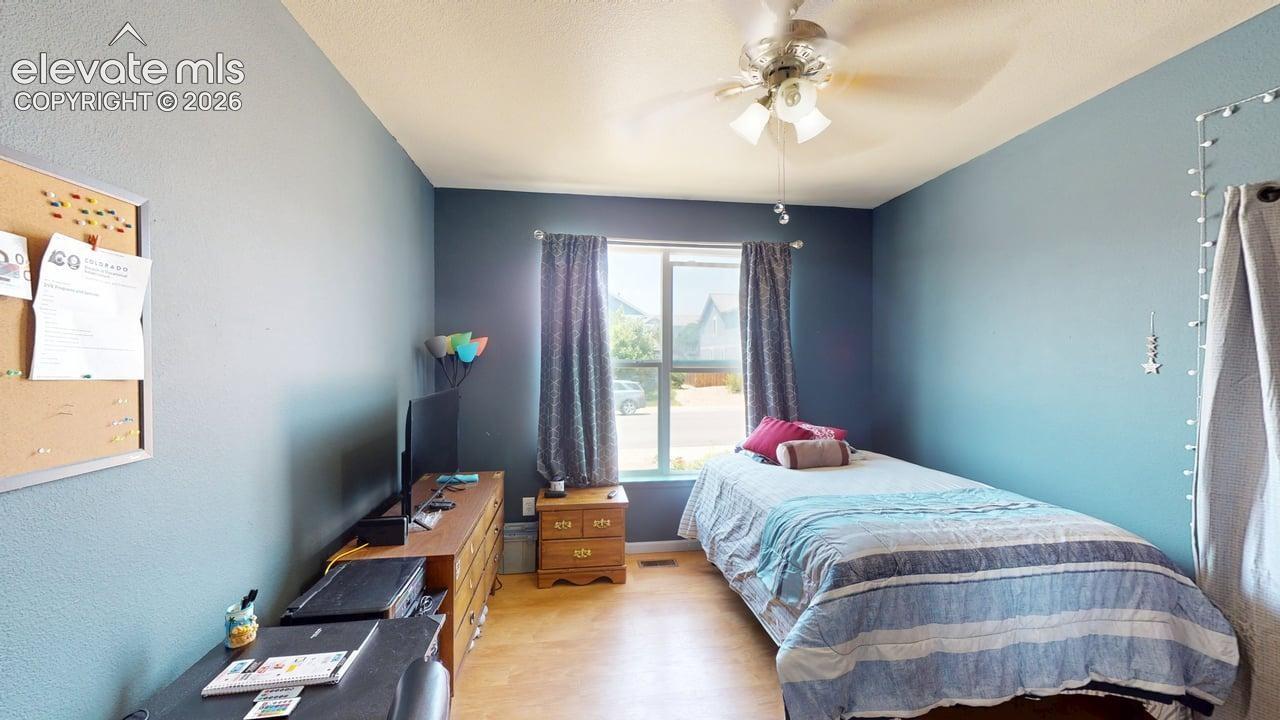 Room featuring light-colored flooring, a window with curtains, and a ceiling fan with integrated lighting