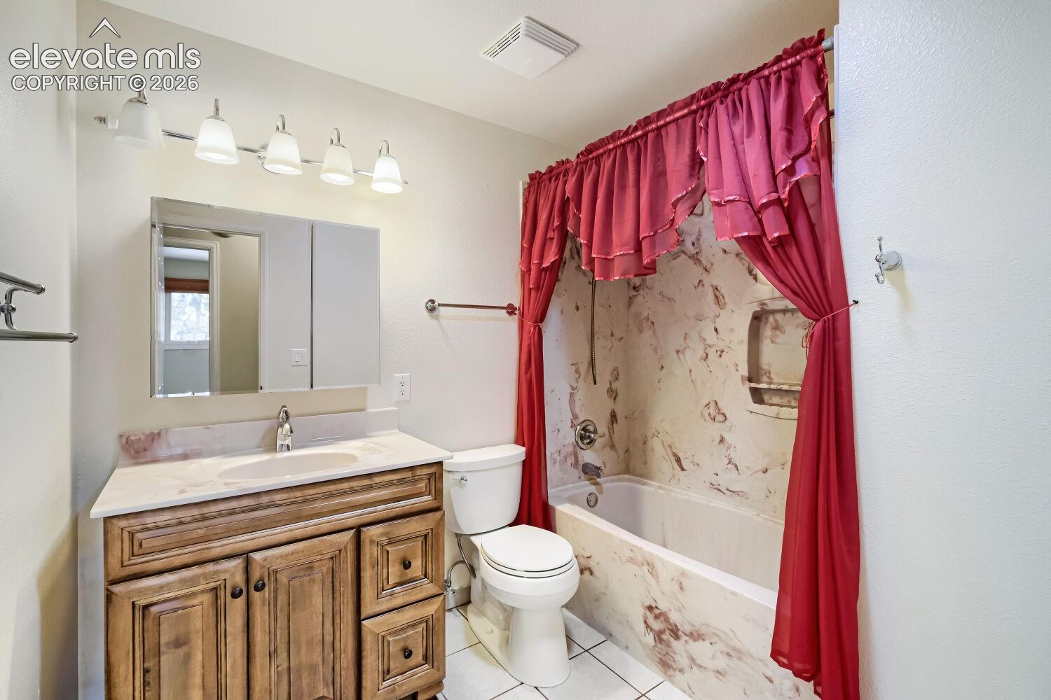 Vanity with a single basin sink, wall-mounted lighting, and a mirrored medicine cabinet