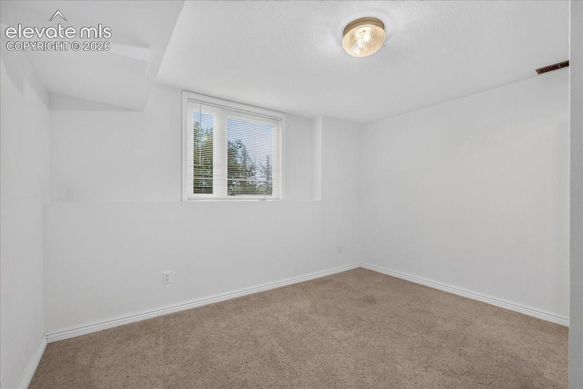 Neutral-toned interior space featuring wall-to-wall carpeting, a recessed window, and a central ceiling-mounted light fixture