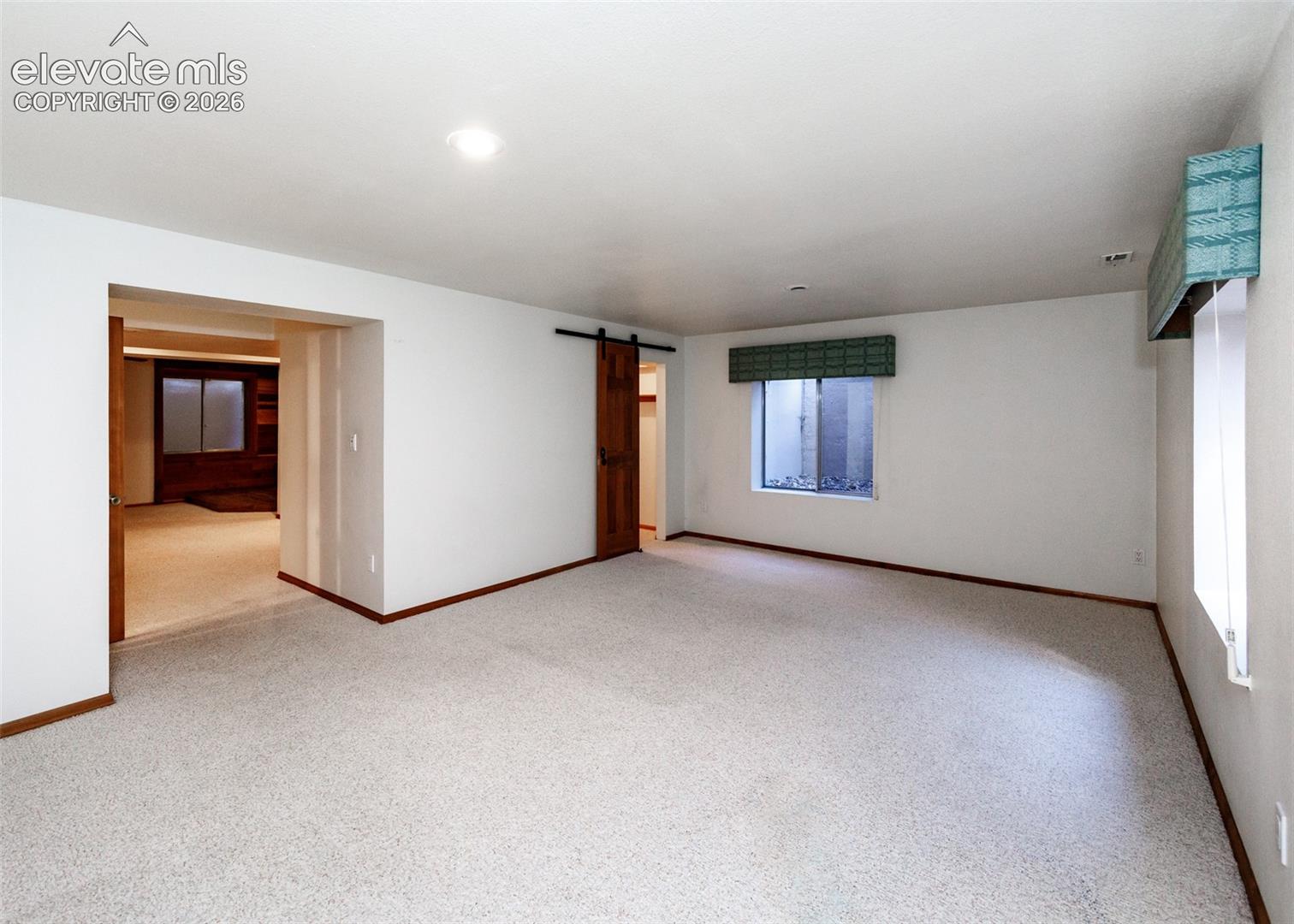Carpeted flooring, recessed lighting, and a barn door entry
