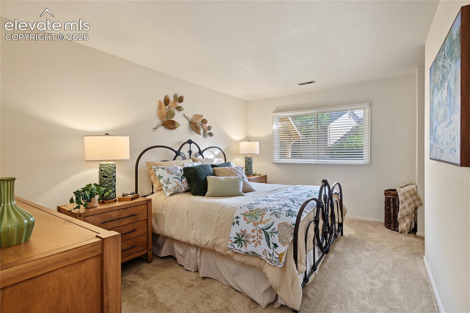 Carpeted bedroom featuring a window with blinds, light-colored walls, and a recessed ceiling light