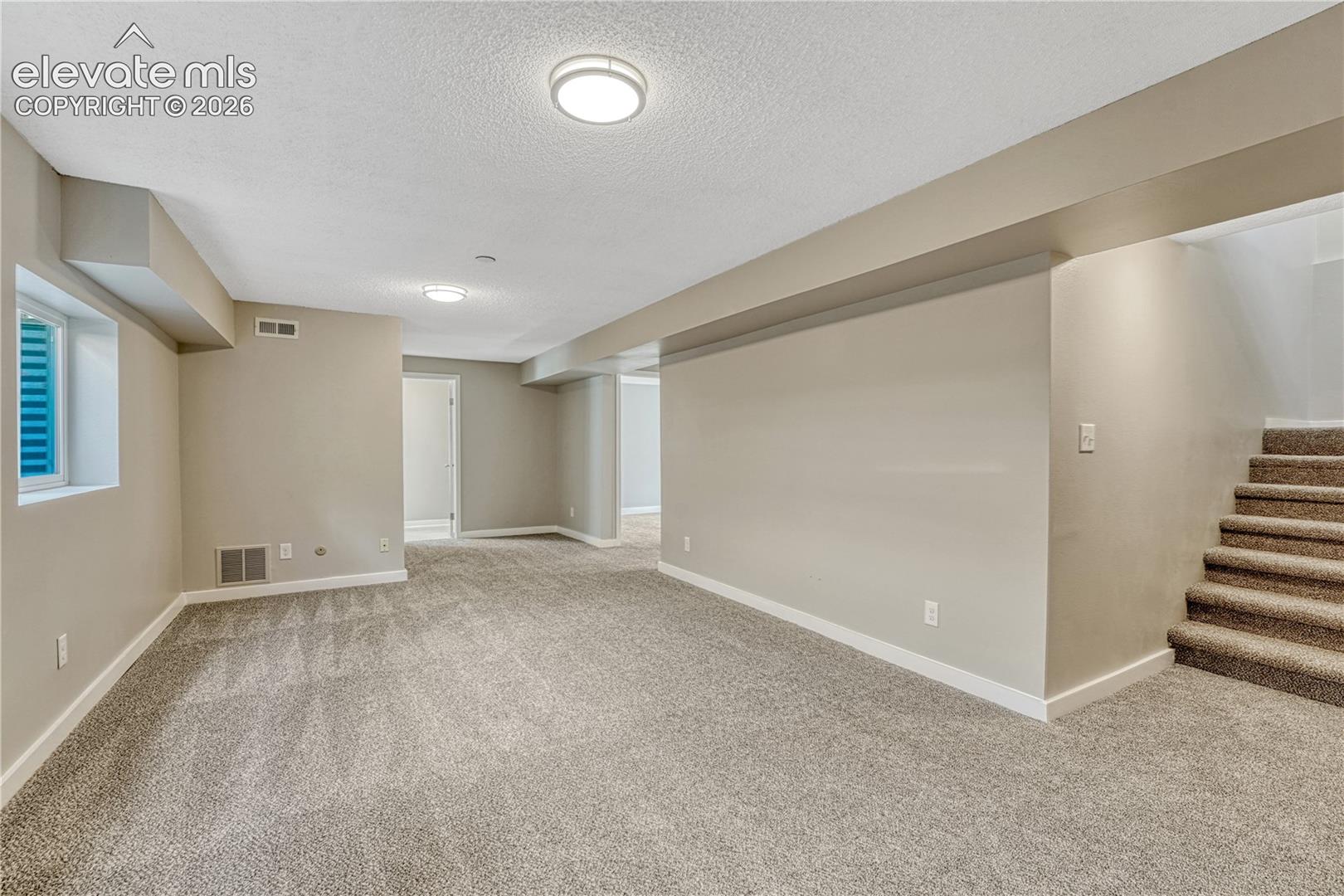 Carpeted living area with neutral wall tones, recessed lighting, and a white-trimmed window