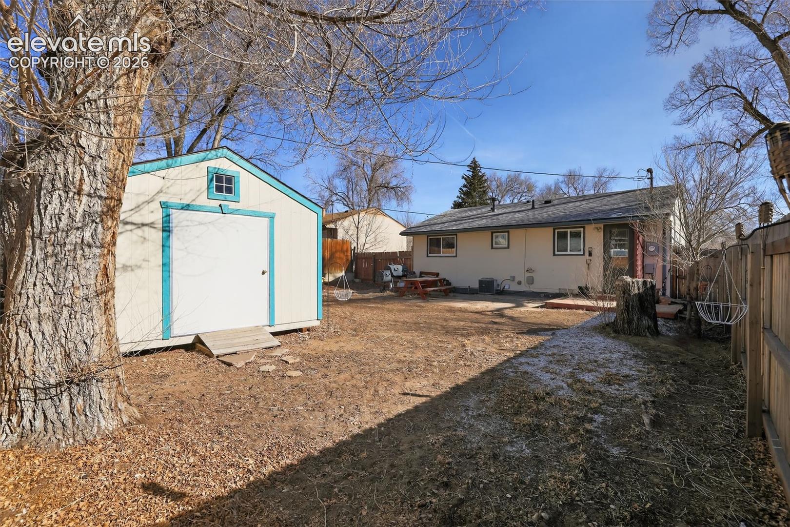 Backyard featuring a detached storage shed, a wood fence, and a rear stucco exterior