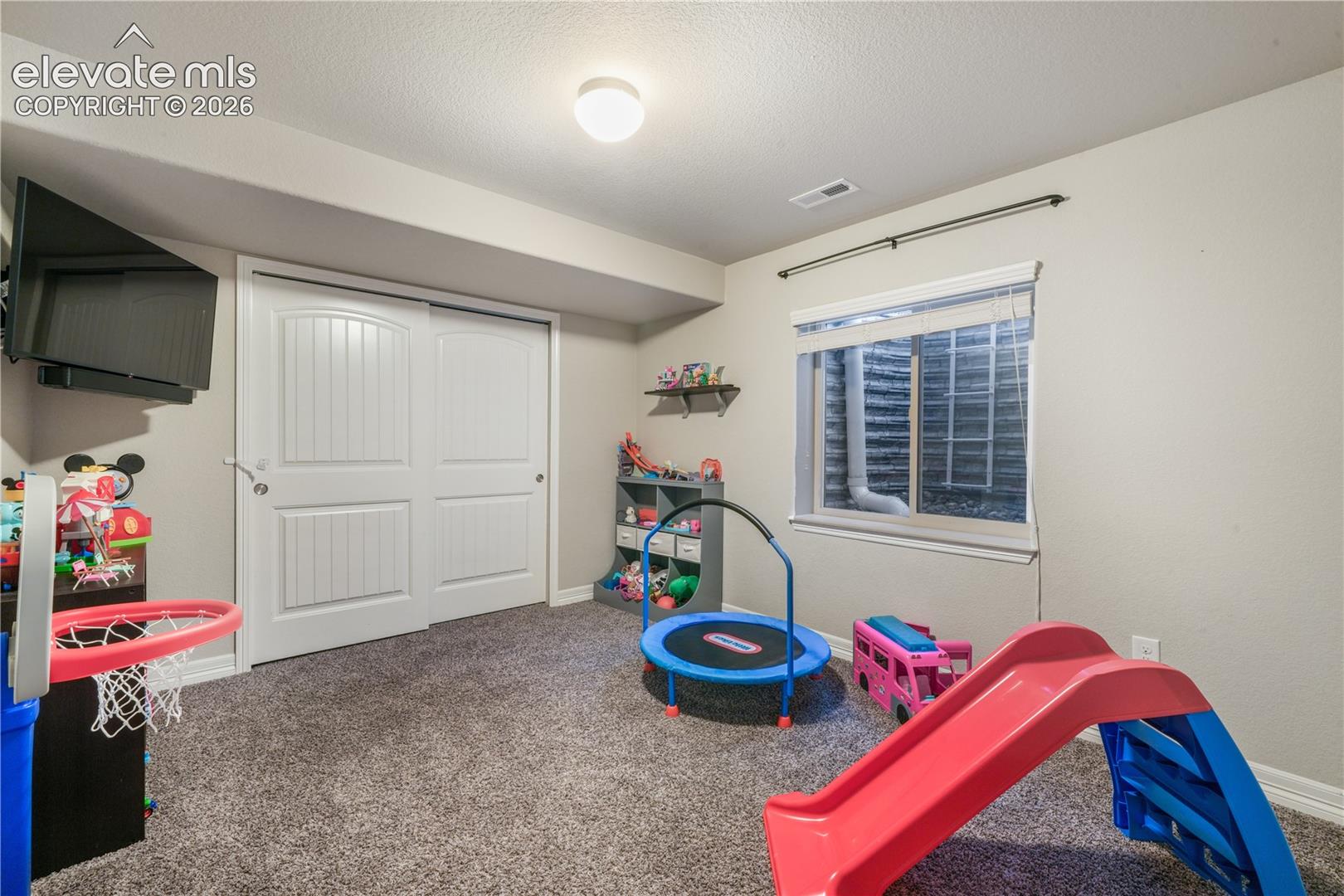 Carpeted floor, sliding barn-style closet doors, recessed window, and flush-mount ceiling lighting
