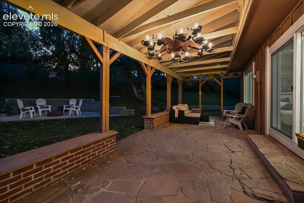 Covered outdoor living area featuring a flagstone patio, exposed beam ceiling, and a decorative chandelier from the original Howard Johnson Hotel