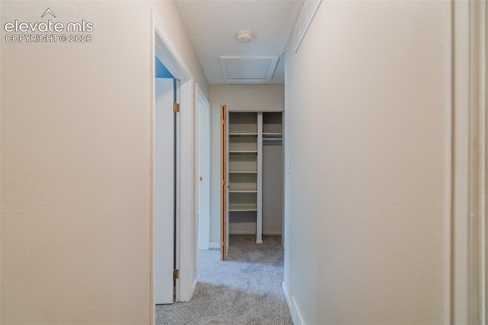 Hallway featuring light-toned walls, textured ceiling, and carpeted flooring