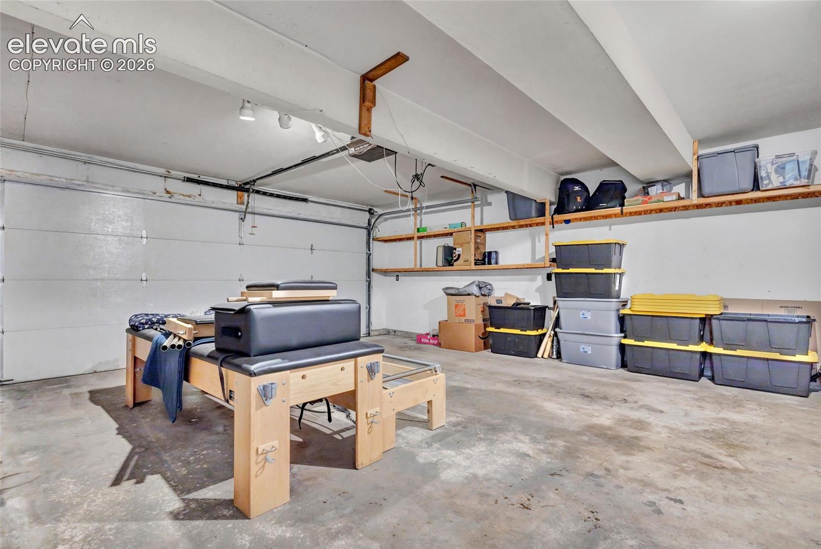 Spacious garage featuring a concrete floor, built-in overhead shelving, and a large garage door