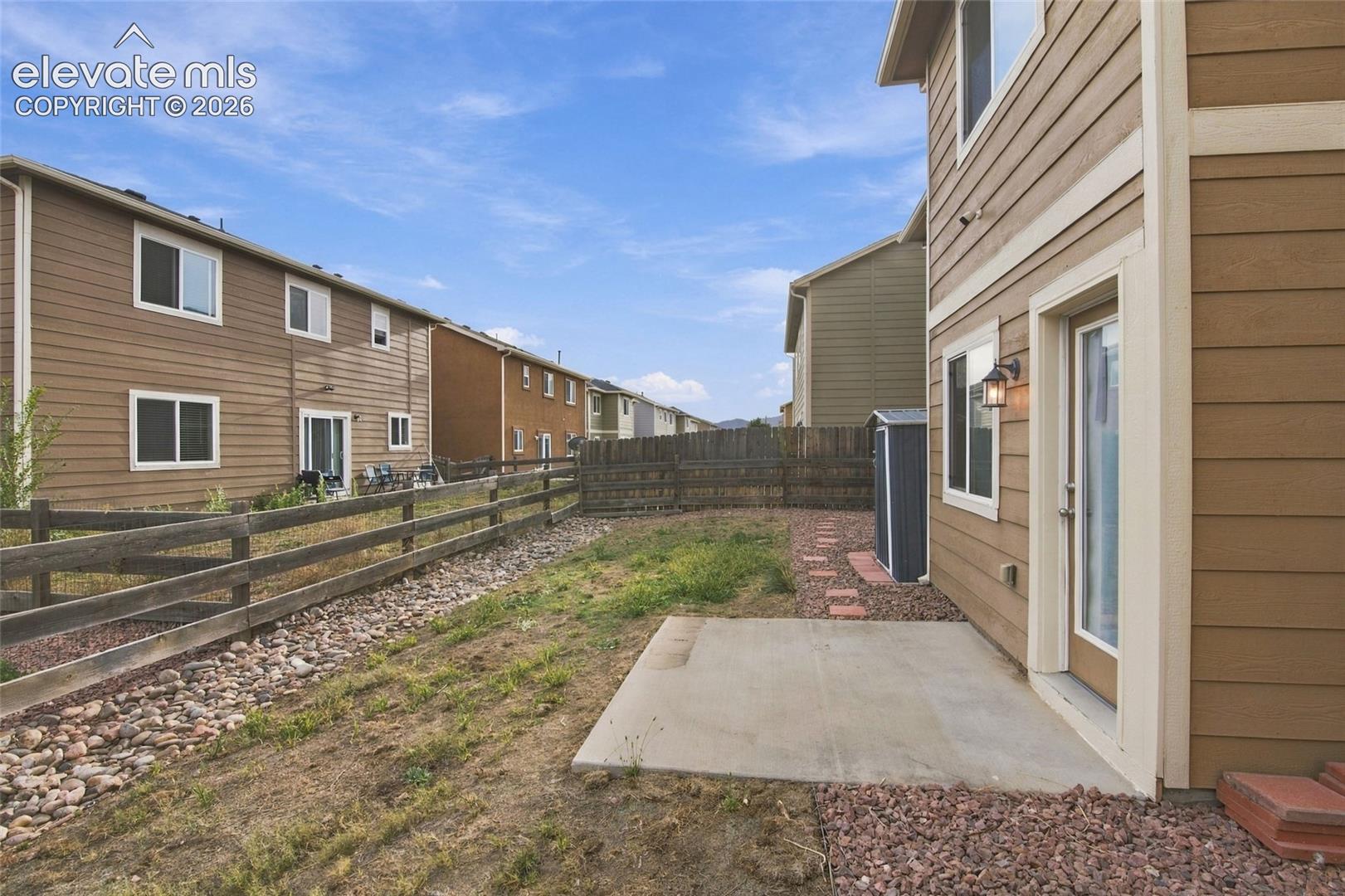Exterior space featuring horizontal siding, a concrete patio, and a post-and-rail wood fence