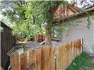 Exterior side yard featuring a wood picket fence, brick siding, and mature landscaping