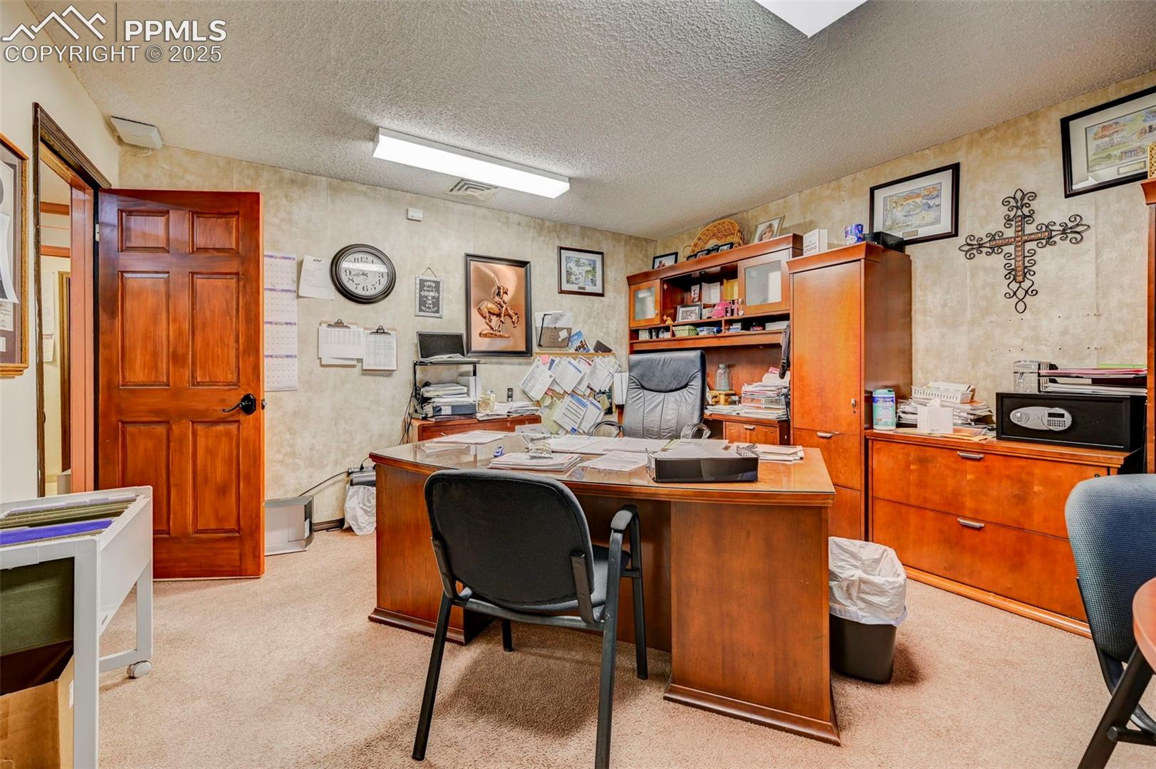 Carpeted office space with a textured ceiling