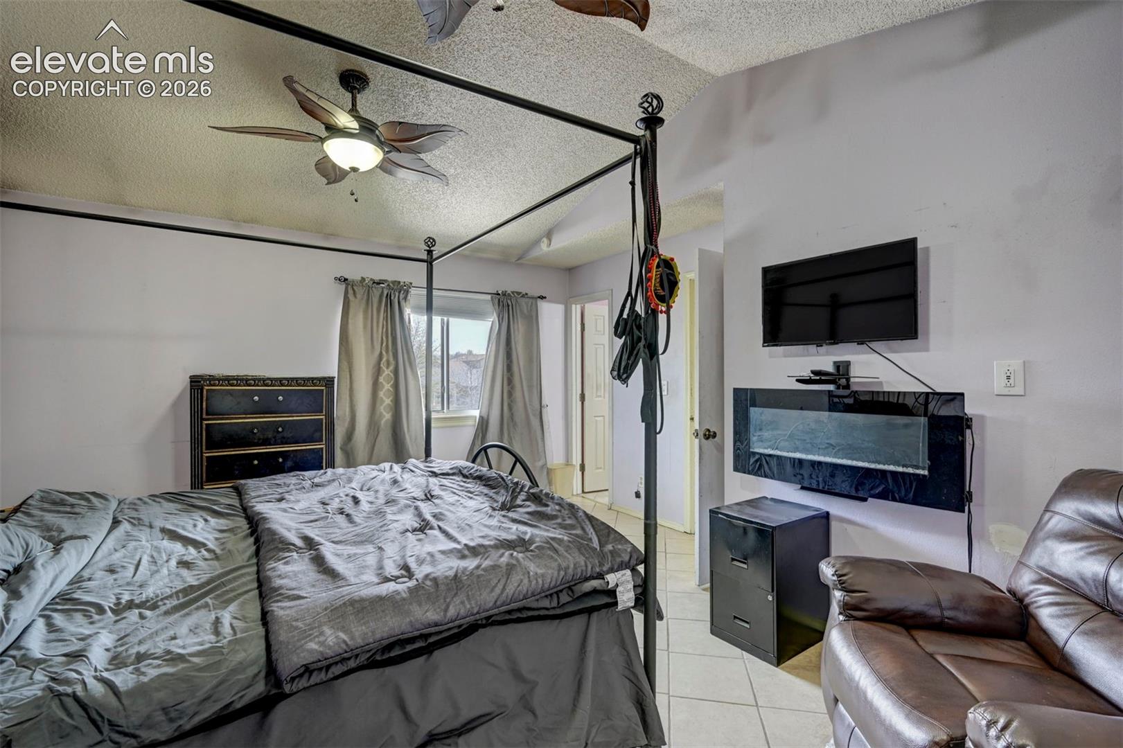 Spacious room featuring a ceiling fan with integrated lighting, a window with drapery, and a wall-mounted entertainment setup