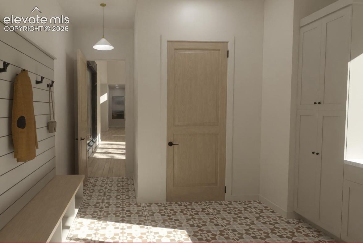 Patterned tile flooring, built-in storage bench, white shiplap wall, light wood-finish door, and integrated white cabinetry