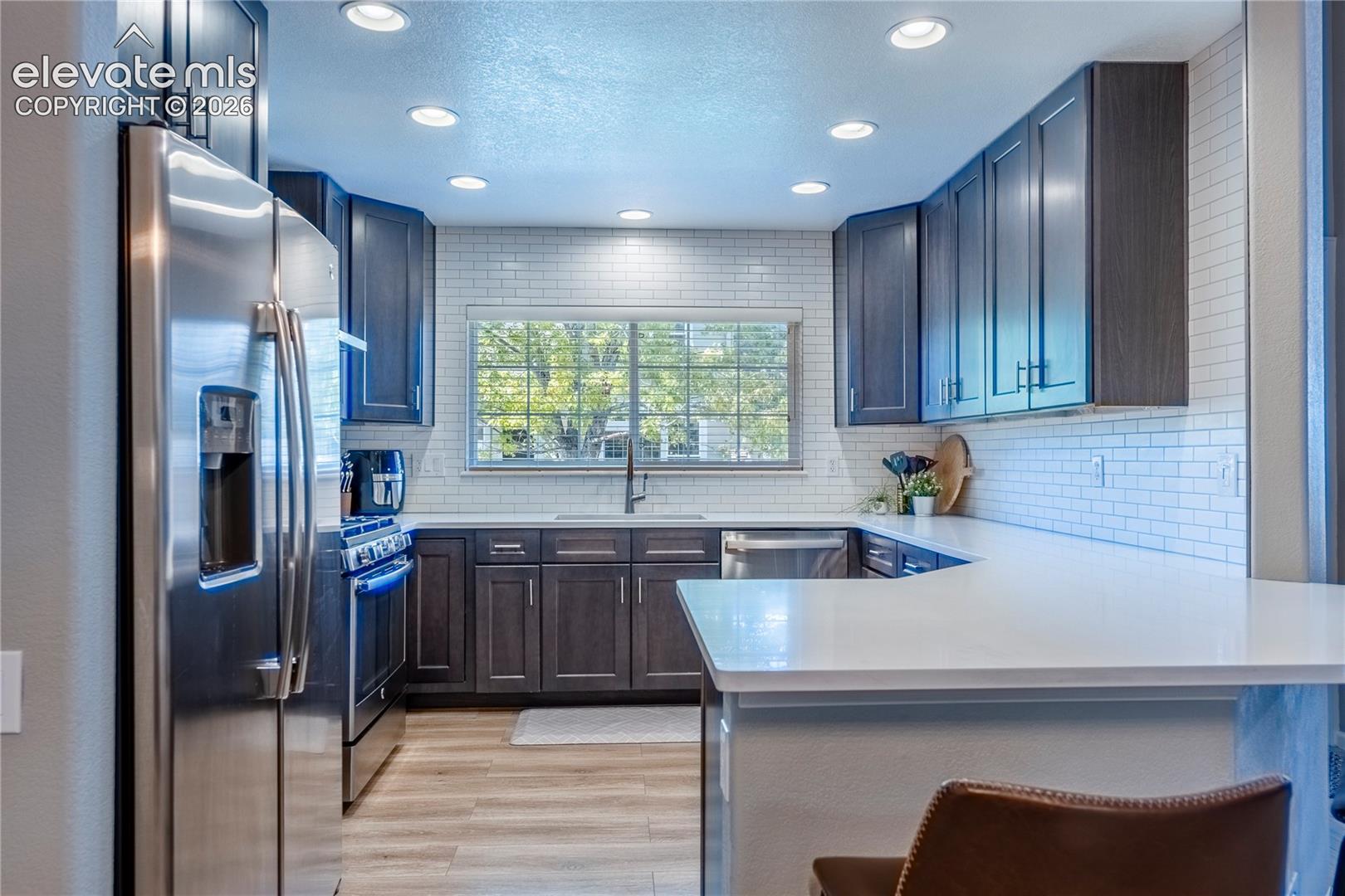 Kitchen featuring dark cabinetry, white countertops, subway tile backsplash, stainless steel appliances, and recessed lighting