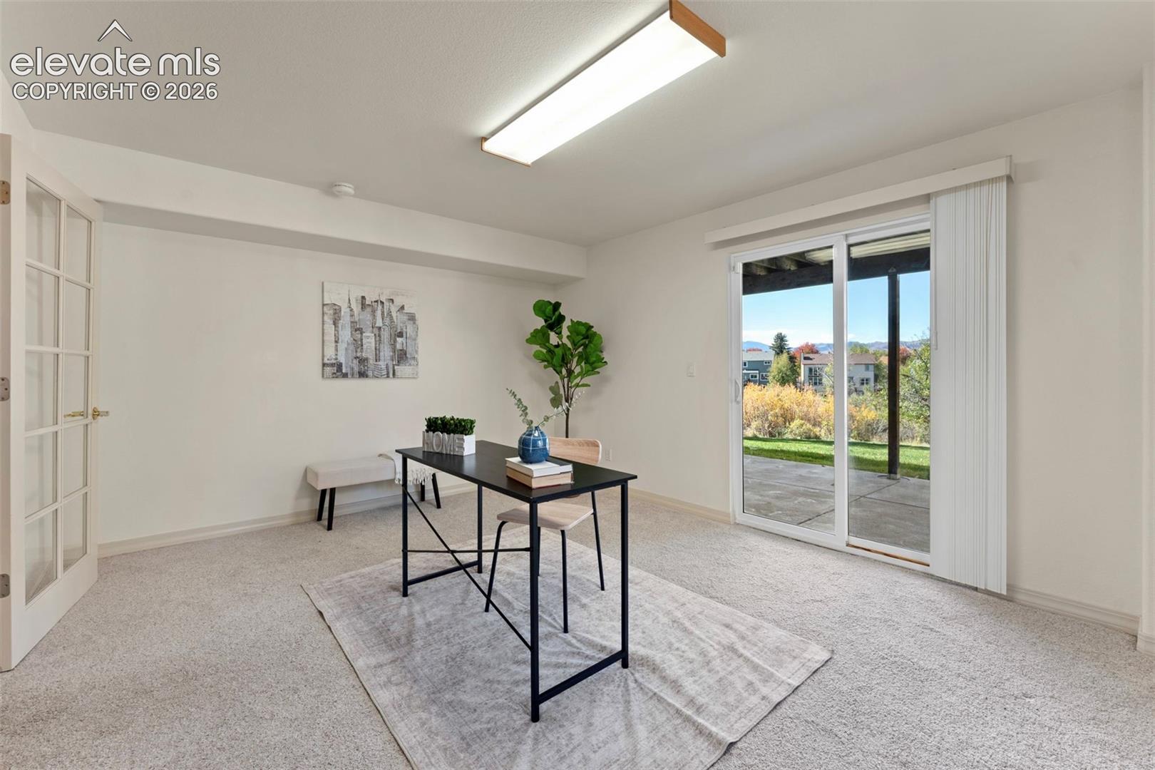 Room featuring neutral carpeting, sliding glass doors, a multi-pane glass door, and a rectangular ceiling light fixture