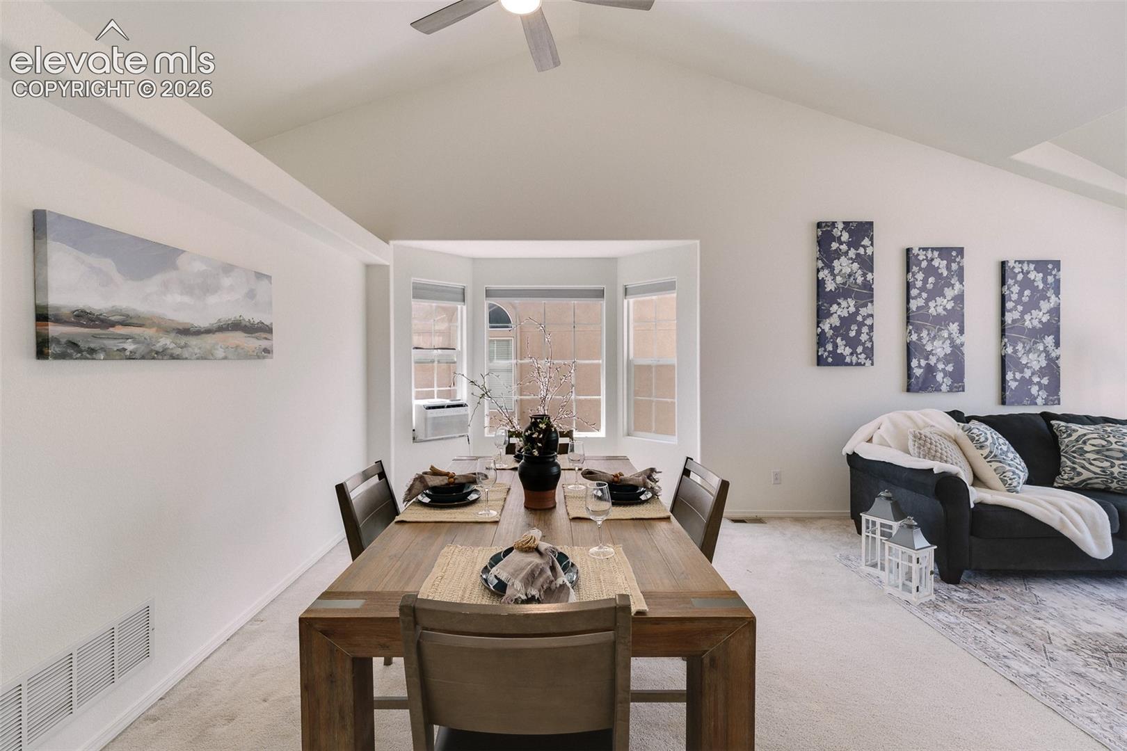 Vaulted ceiling with ceiling fan, bay window, and a built-in wall niche