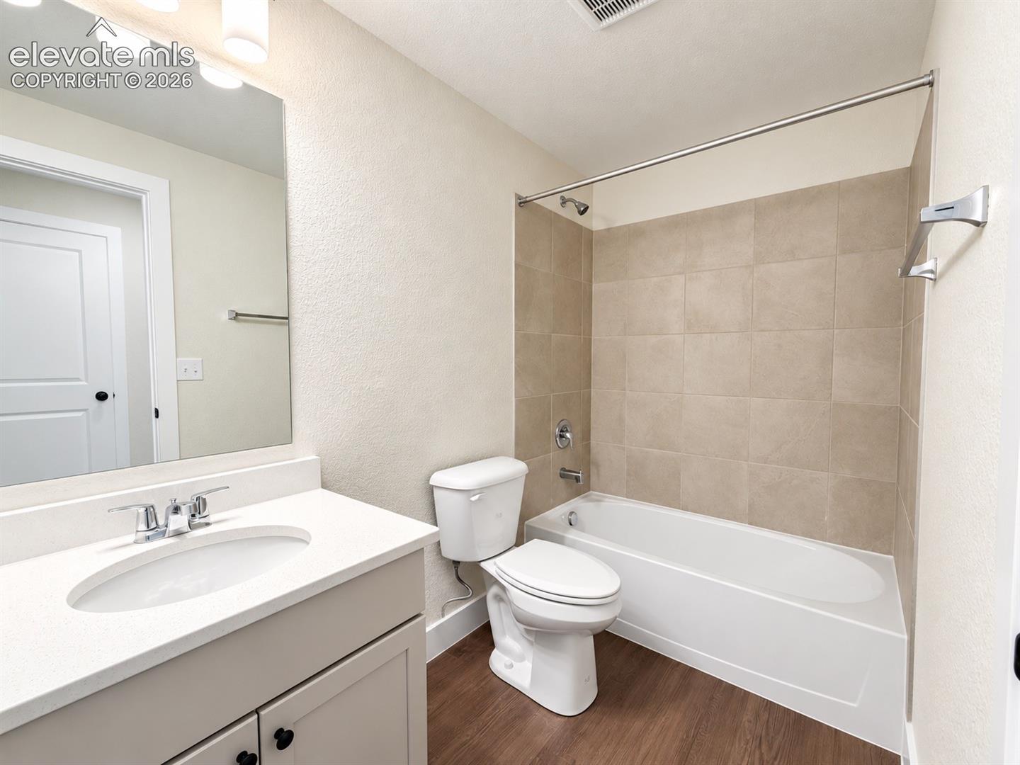 Bathroom with a white vanity, integrated sink, chrome faucet, and rectangular mirror