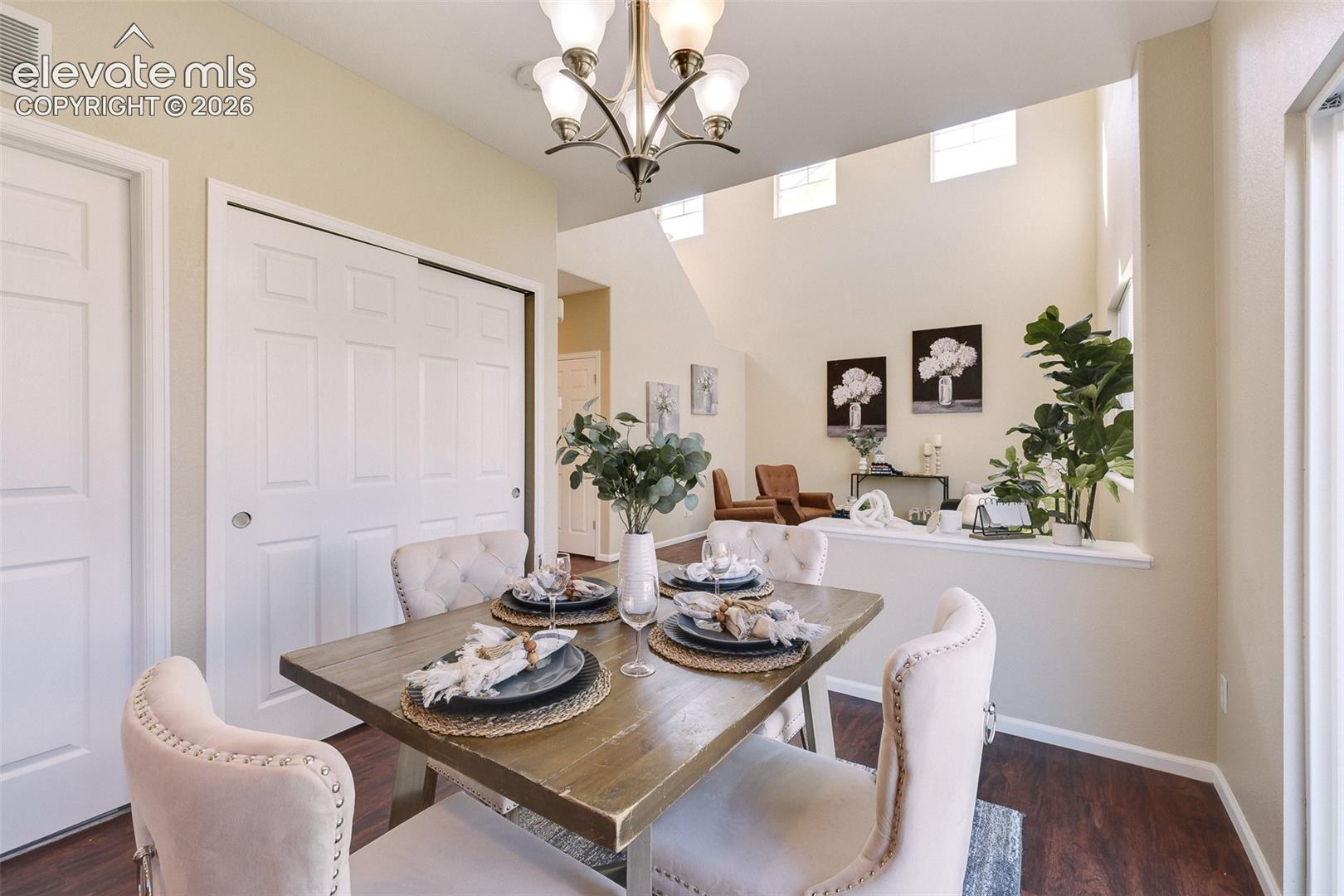 Vaulted ceilings with clerestory windows, wood-finish flooring, and a multi-arm chandelier