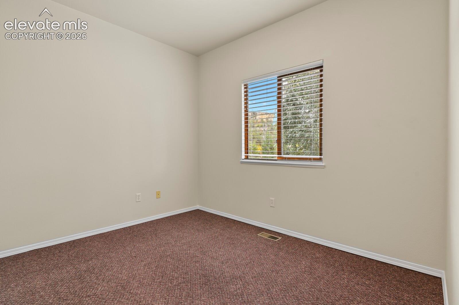 Neutral wall paint, textured carpeting, and a sliding window featuring horizontal blinds