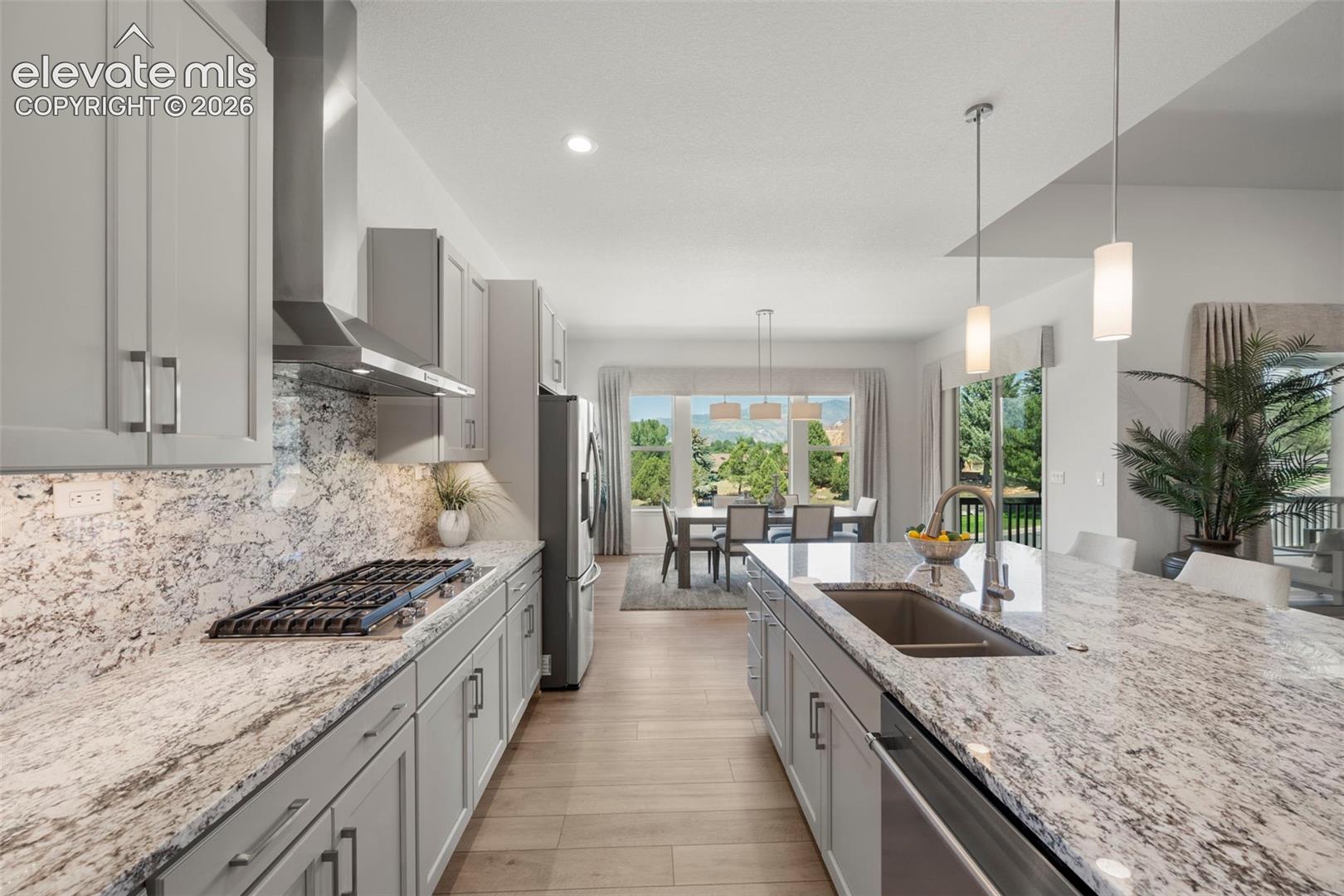 Kitchen featuring light-toned cabinetry, stainless steel appliances, a gas cooktop, and a large island with an undermount sink and pendant lighting