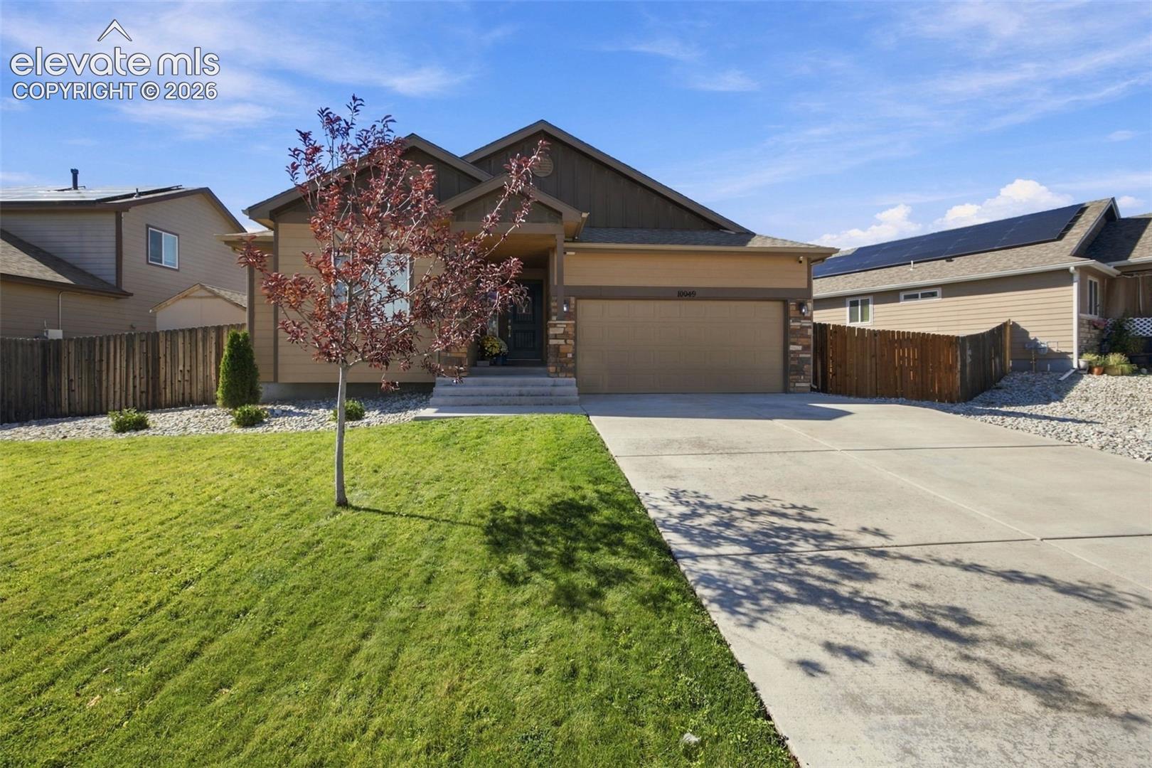 Single-story residence featuring a gabled roofline, stone veneer accents, concrete driveway, and a manicured front lawn