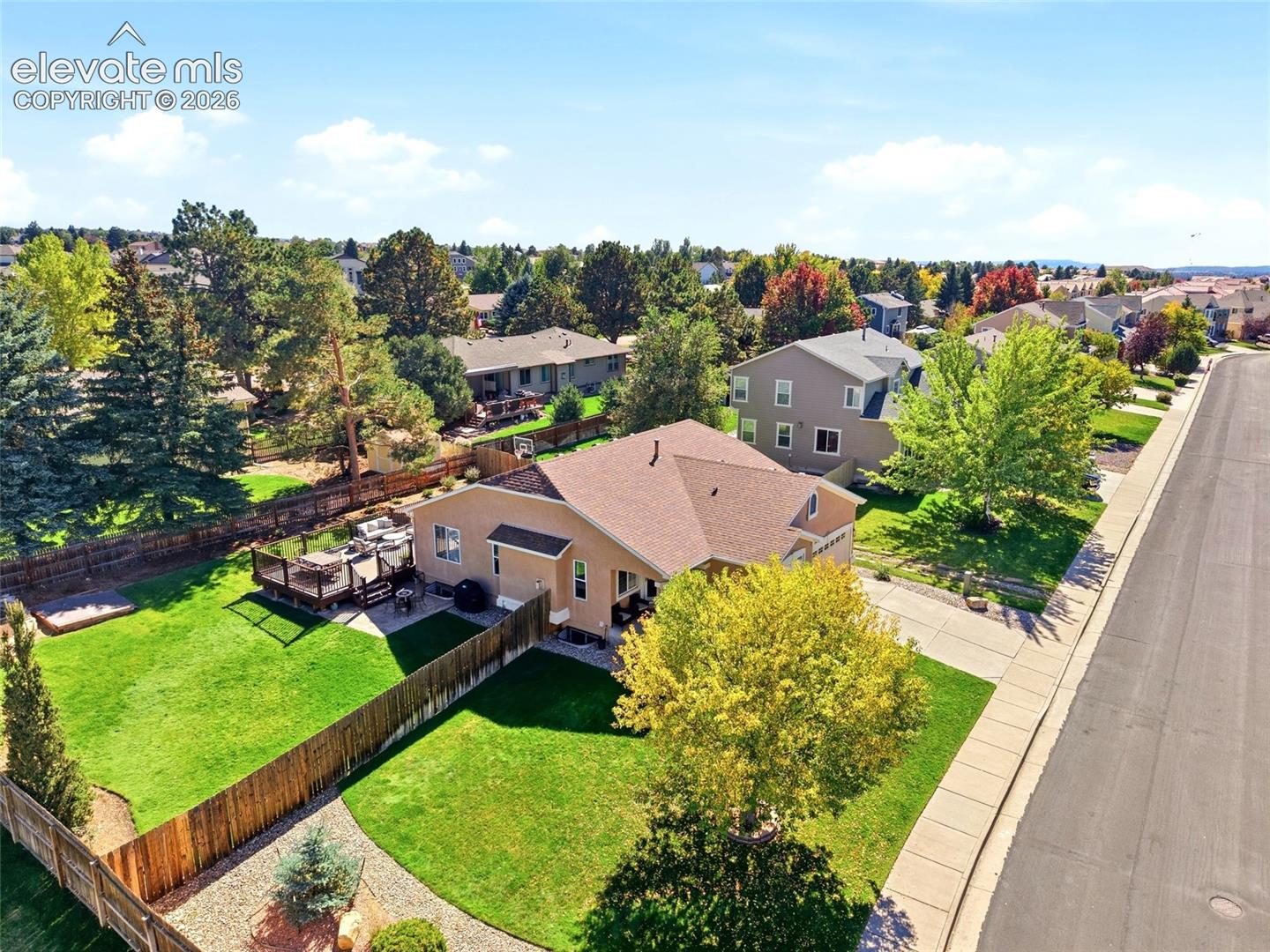 Expansive backyard featuring a manicured lawn, a multi-level wood deck, and a privacy fence