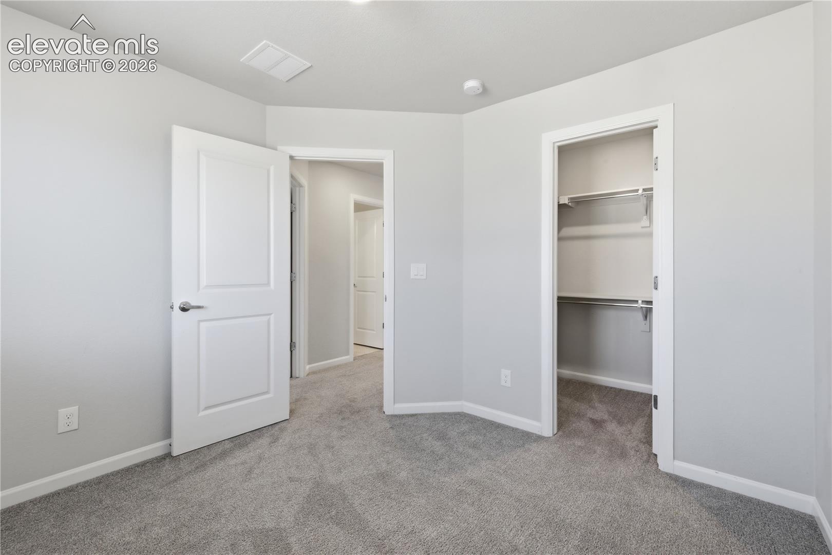 Plush carpeted room featuring a neutral color palette, recessed lighting, and a bi-fold door closet with shelving