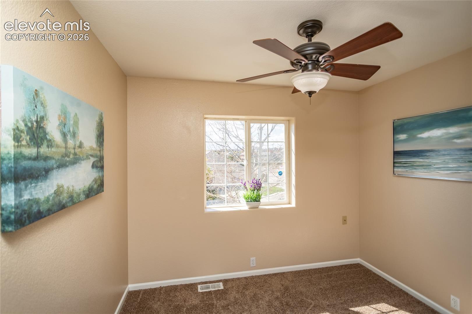 The third upper-level bedroom boasts generous natural light, plush carpet, and a ceiling fan