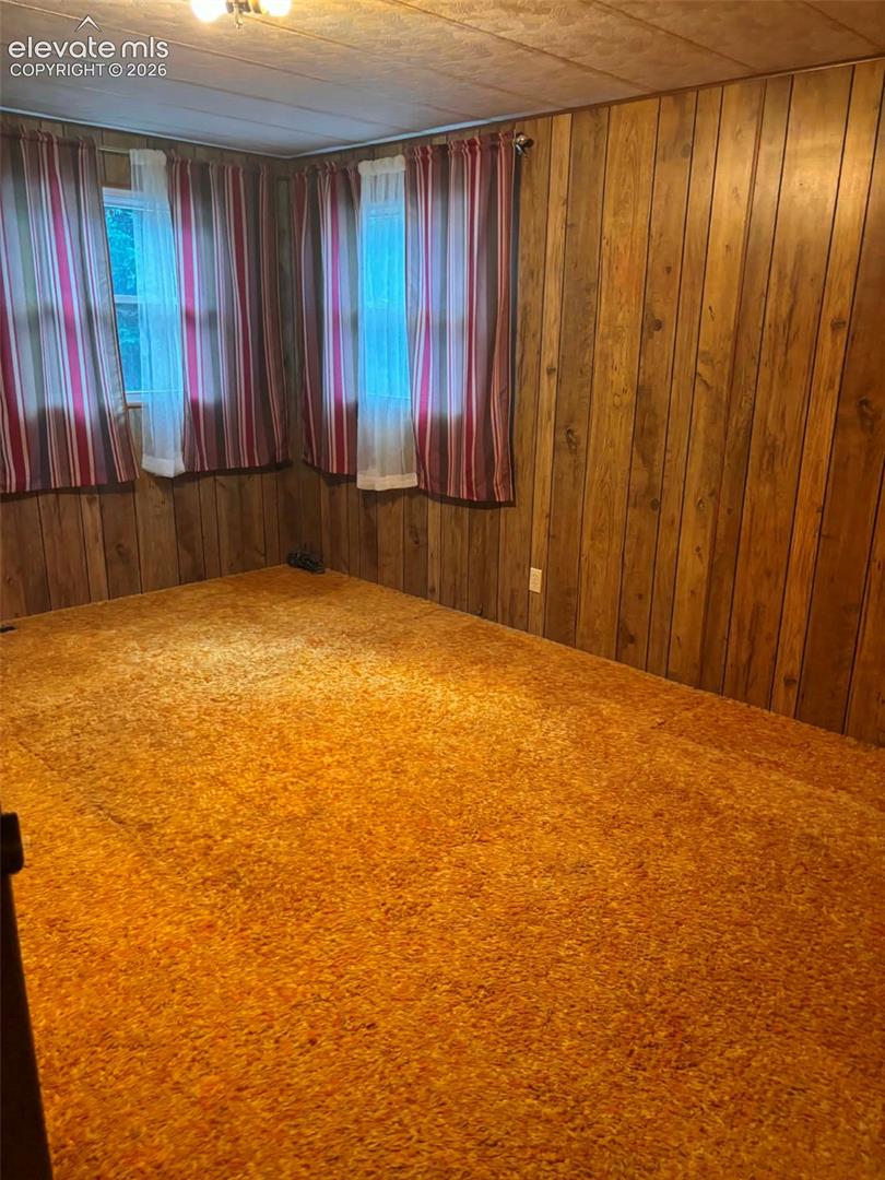 Vertical wood-panelled walls, wall-to-wall carpeting, and double windows with dual-track hardware