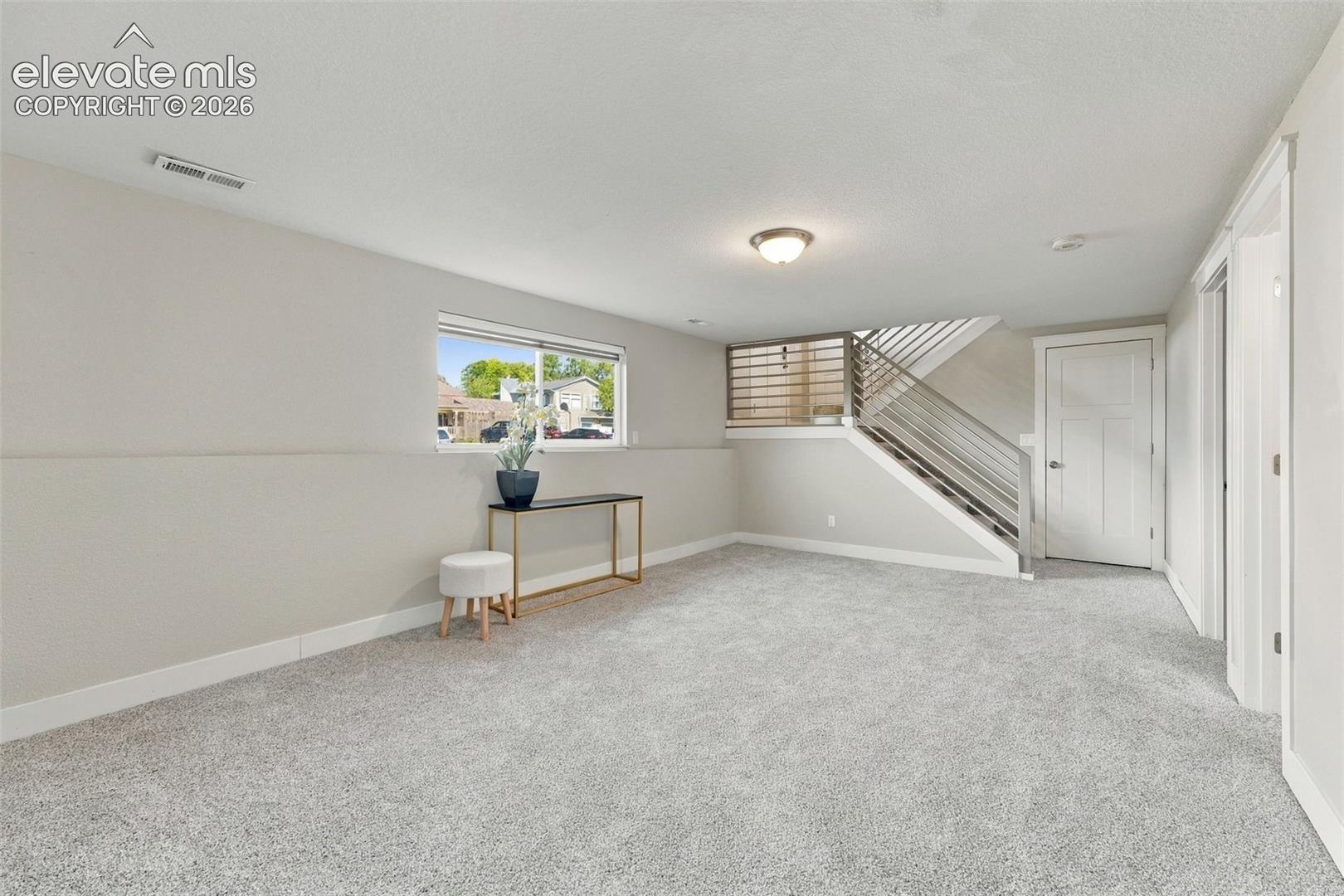 Carpeted living area featuring a window, modern railing staircase, and recessed lighting