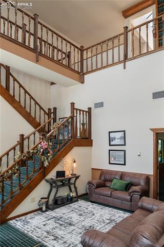 Living room with a high ceiling, carpet, and stairway