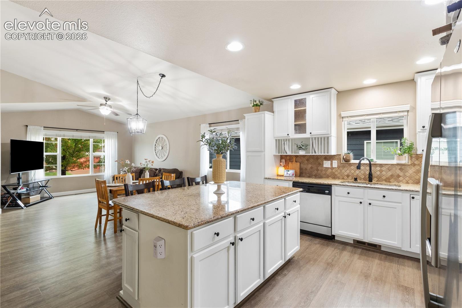 Kitchen featuring a large central island with a stone-finish countertop, white cabinetry, recessed lighting, and wood-finish flooring