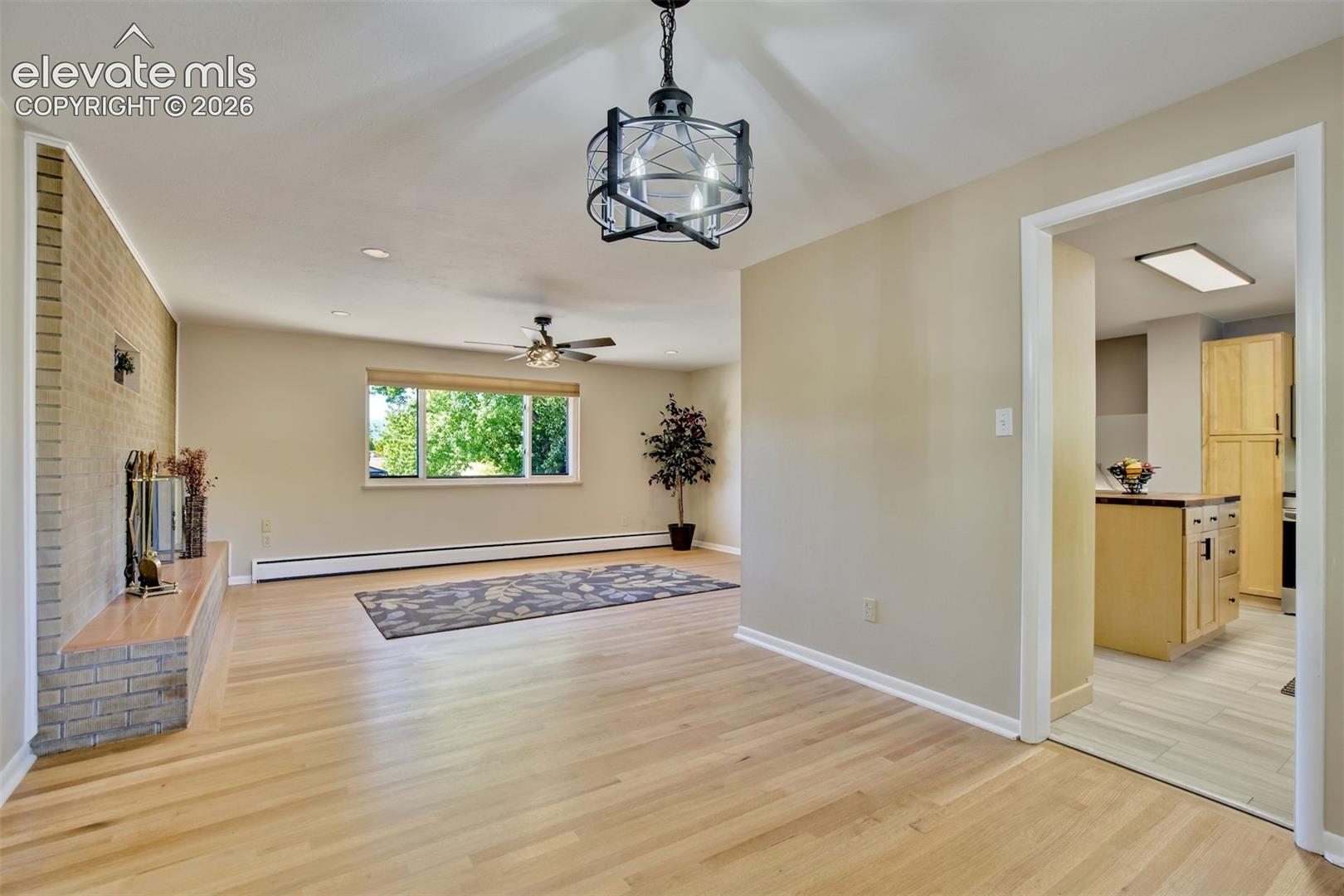 Living space featuring wood-finish flooring, a floor-to-ceiling brick hearth, recessed lighting, and a geometric metal pendant fixture