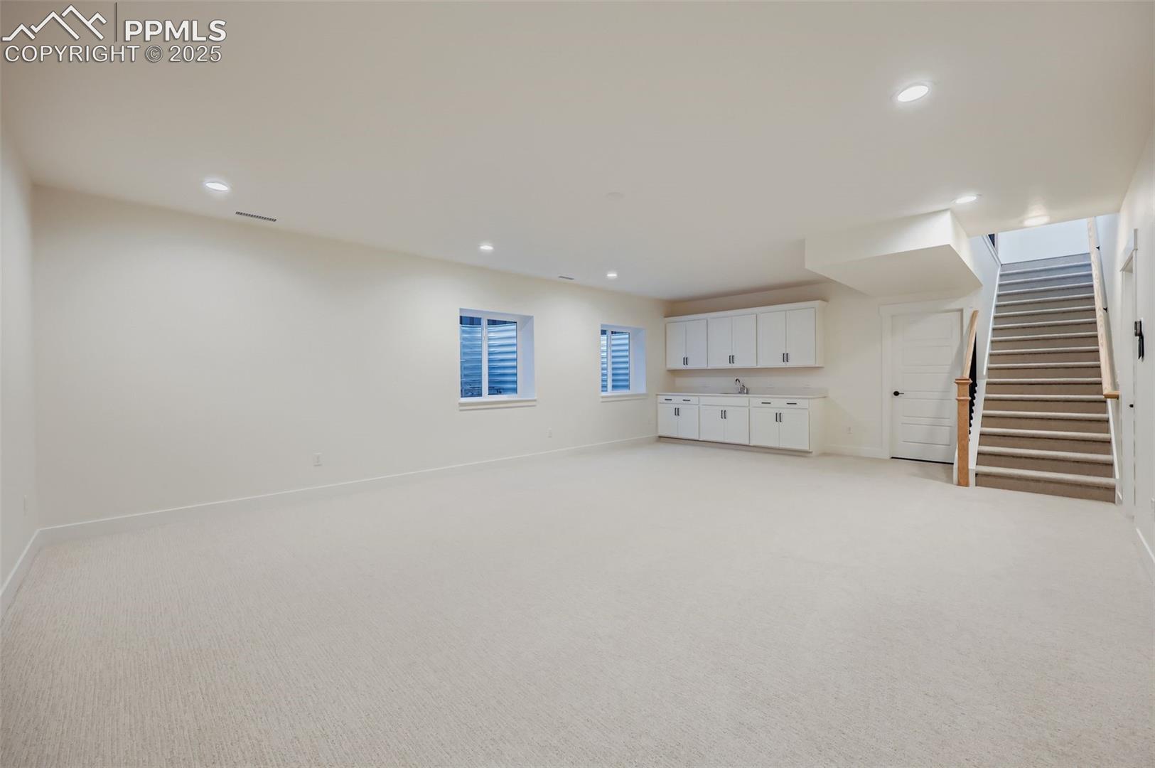 Basement featuring stairs, light colored carpet, and recessed lighting