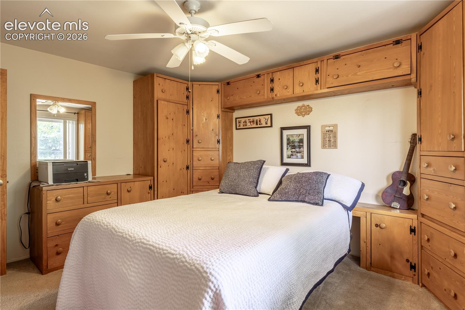 Custom built-in wood cabinetry featuring integrated storage towers, upper bridge cabinets, and dresser drawers, complemented by a ceiling fan with integrated lighting