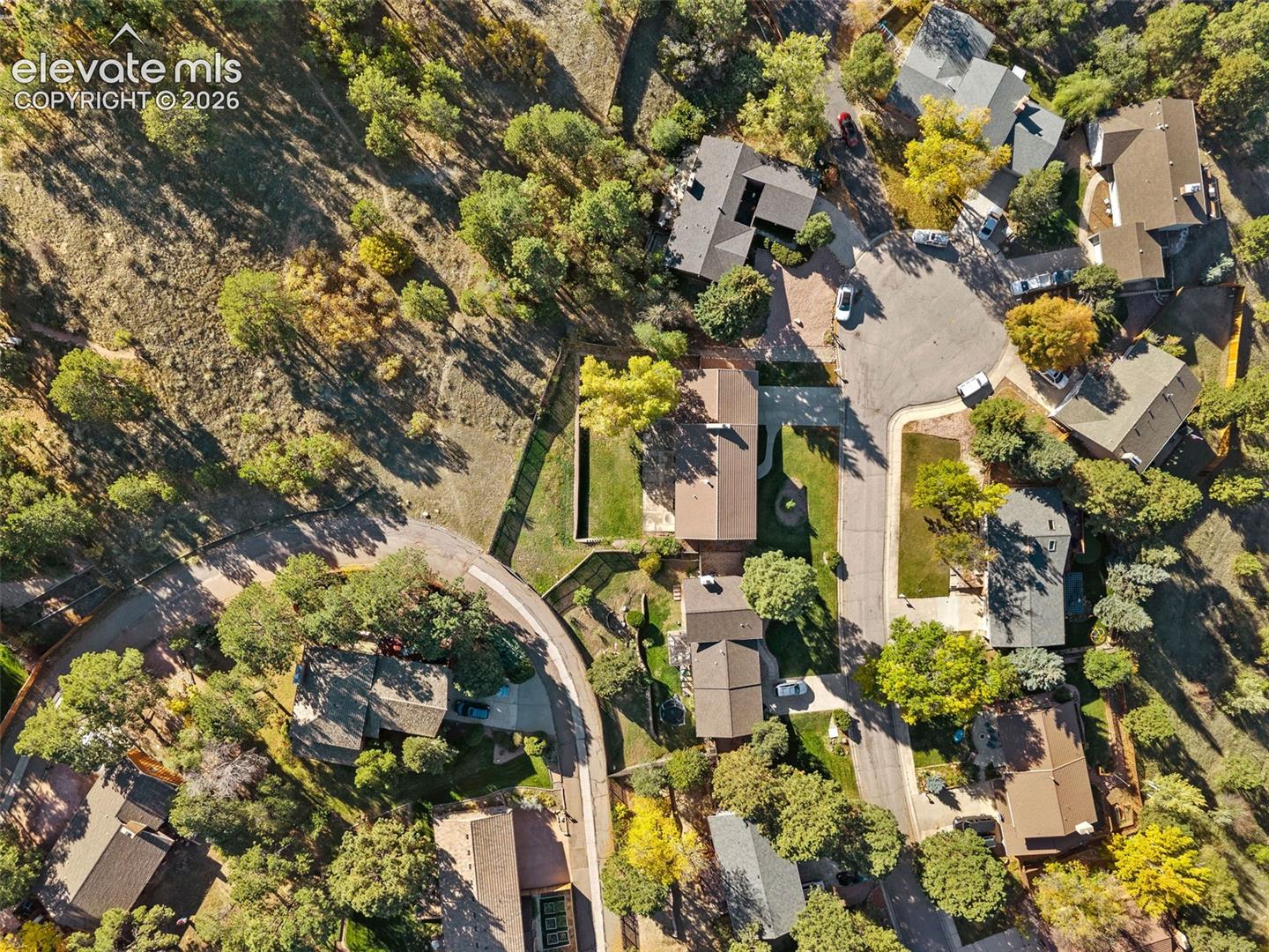 Aerial perspective of a residential cul-de-sac featuring expansive wooded surroundings, mature trees, and paved street infrastructure