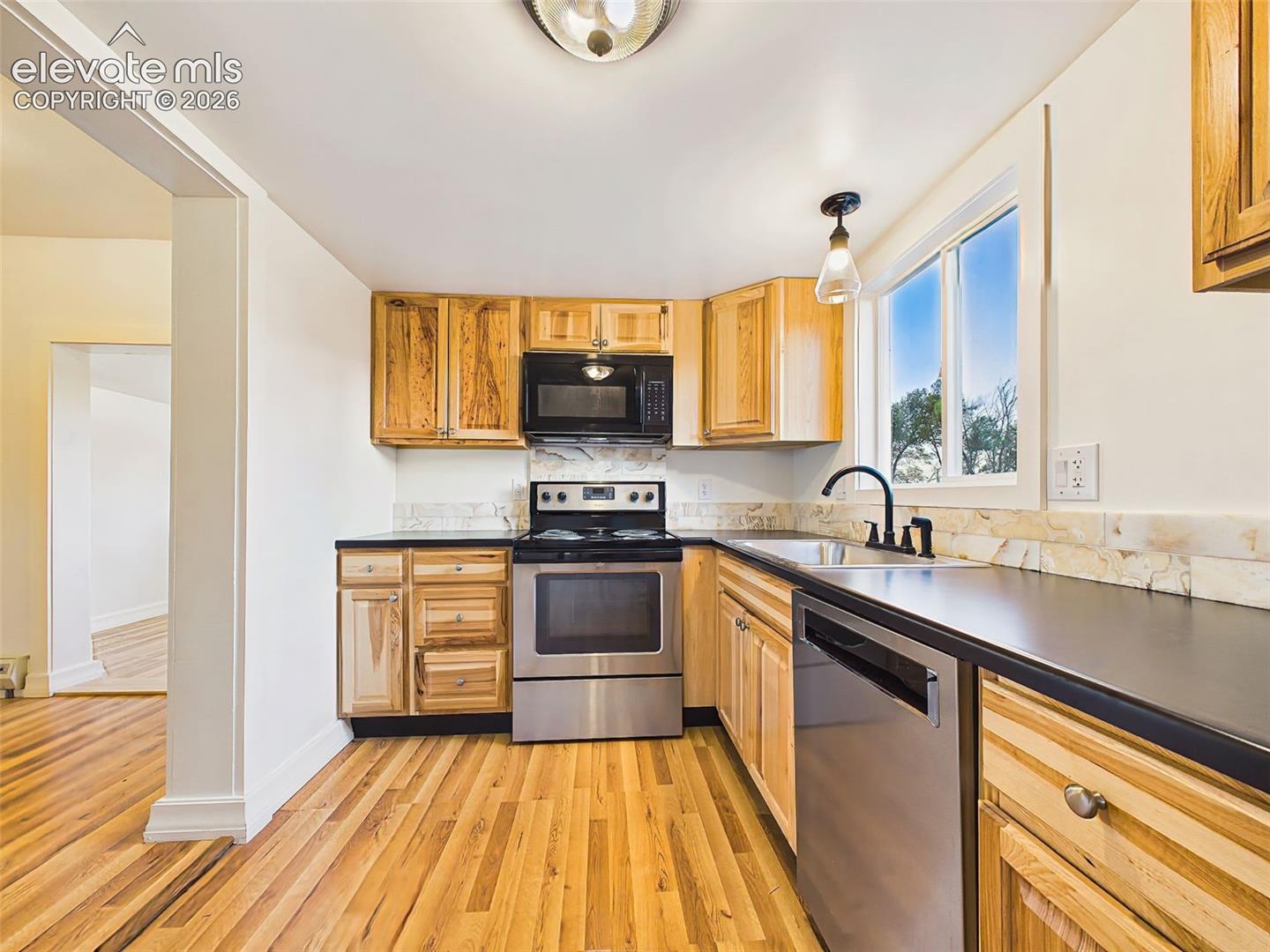 Kitchen – Bright, functional kitchen with ample cabinet storage, stainless steel appliances, and a window overlooking the property.