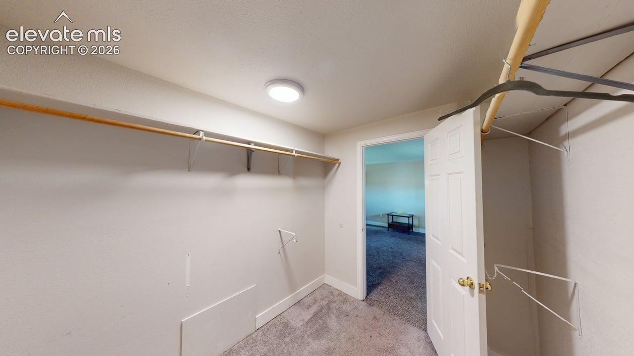 Spacious walk-in closet featuring dual clothing rods with hanging space, carpeted flooring, and recessed ceiling lighting
