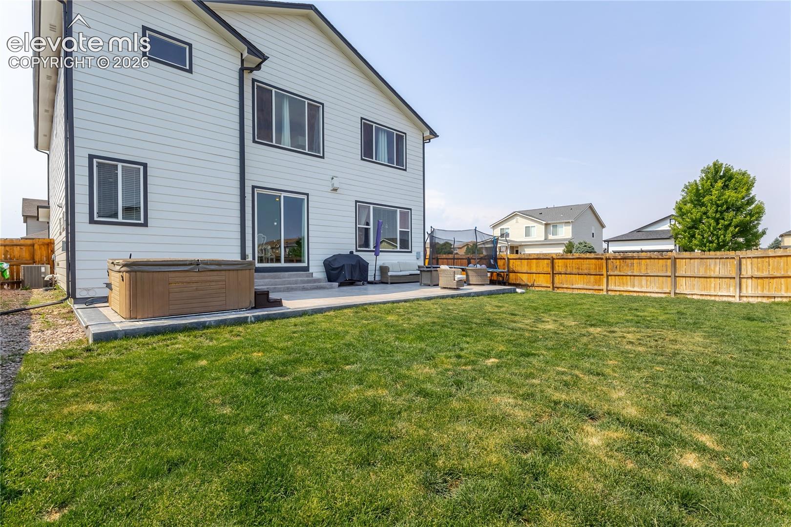 Expansive backyard featuring a manicured lawn and a concrete patio