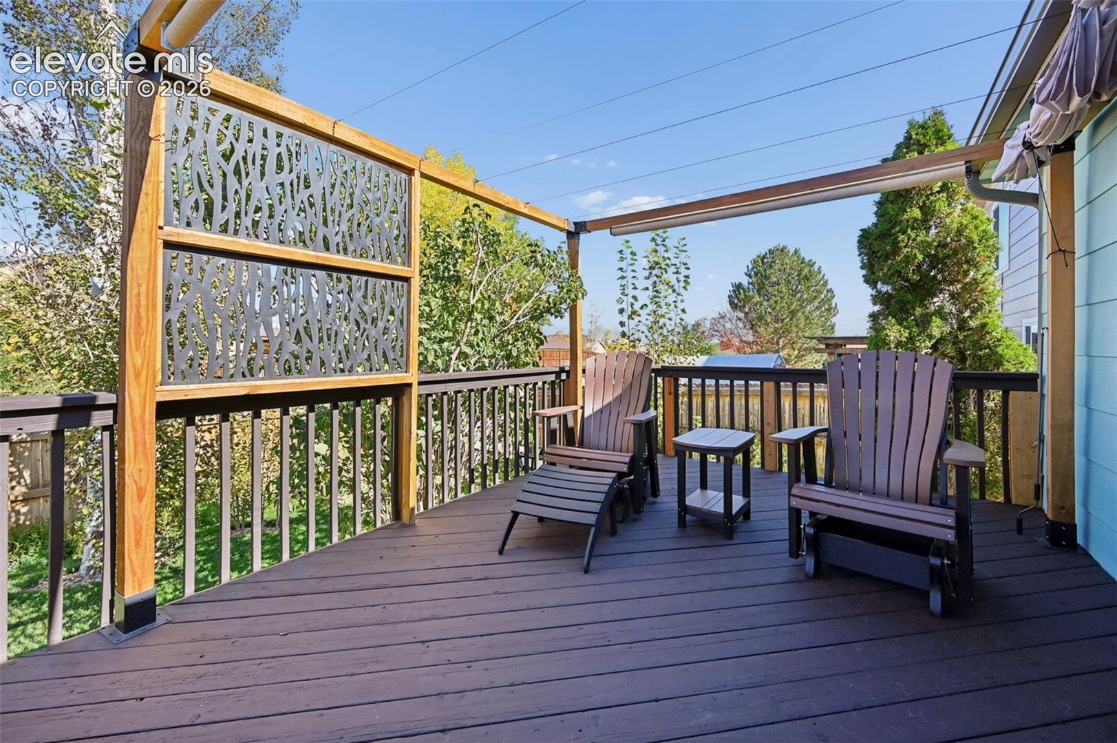 Elevated outdoor deck featuring composite decking, vertical wood-frame privacy screening with decorative metal panels, and perimeter railings