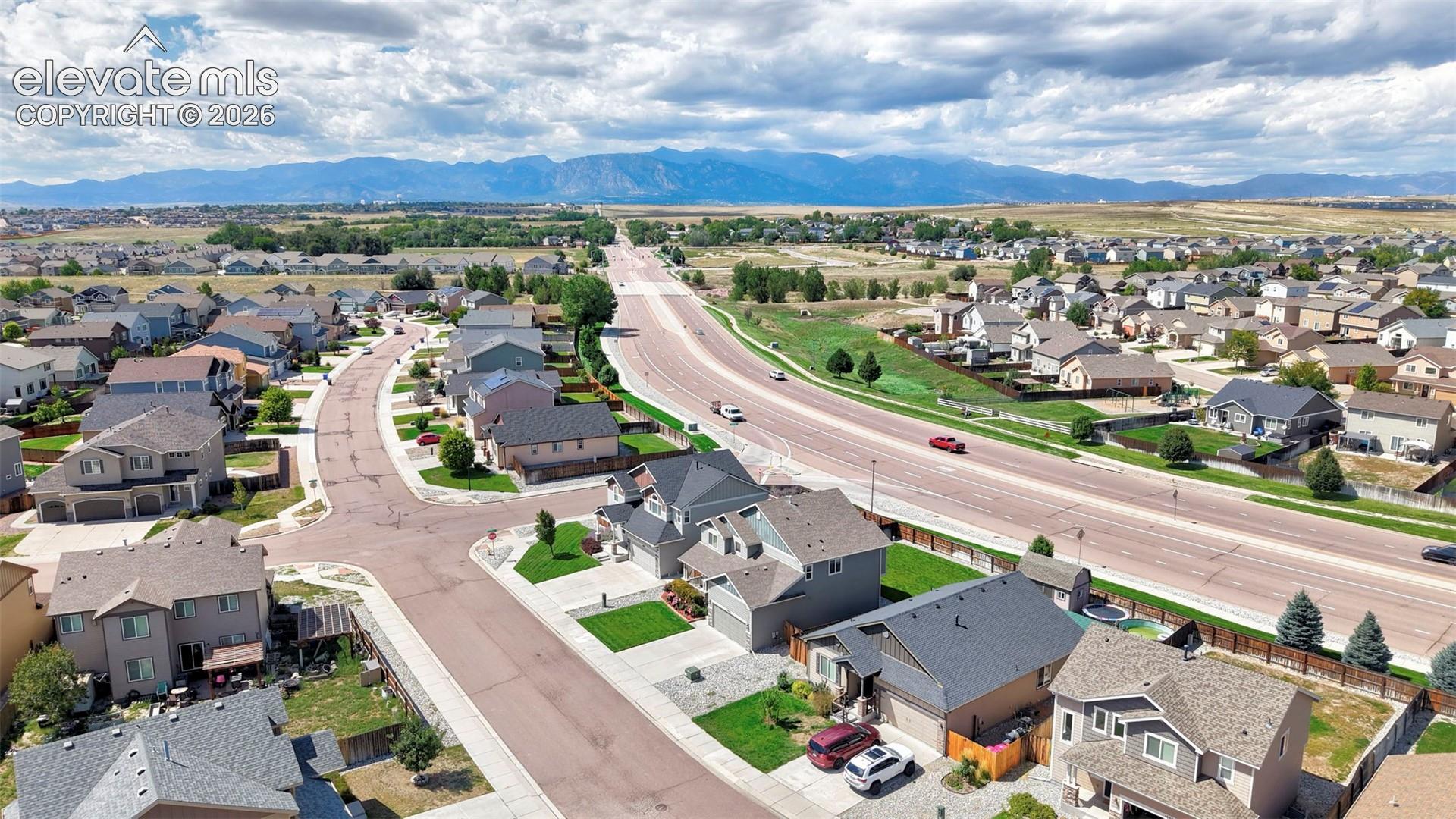 Residential neighborhood with varied architectural styles, mature landscaping, and mountain scenery
