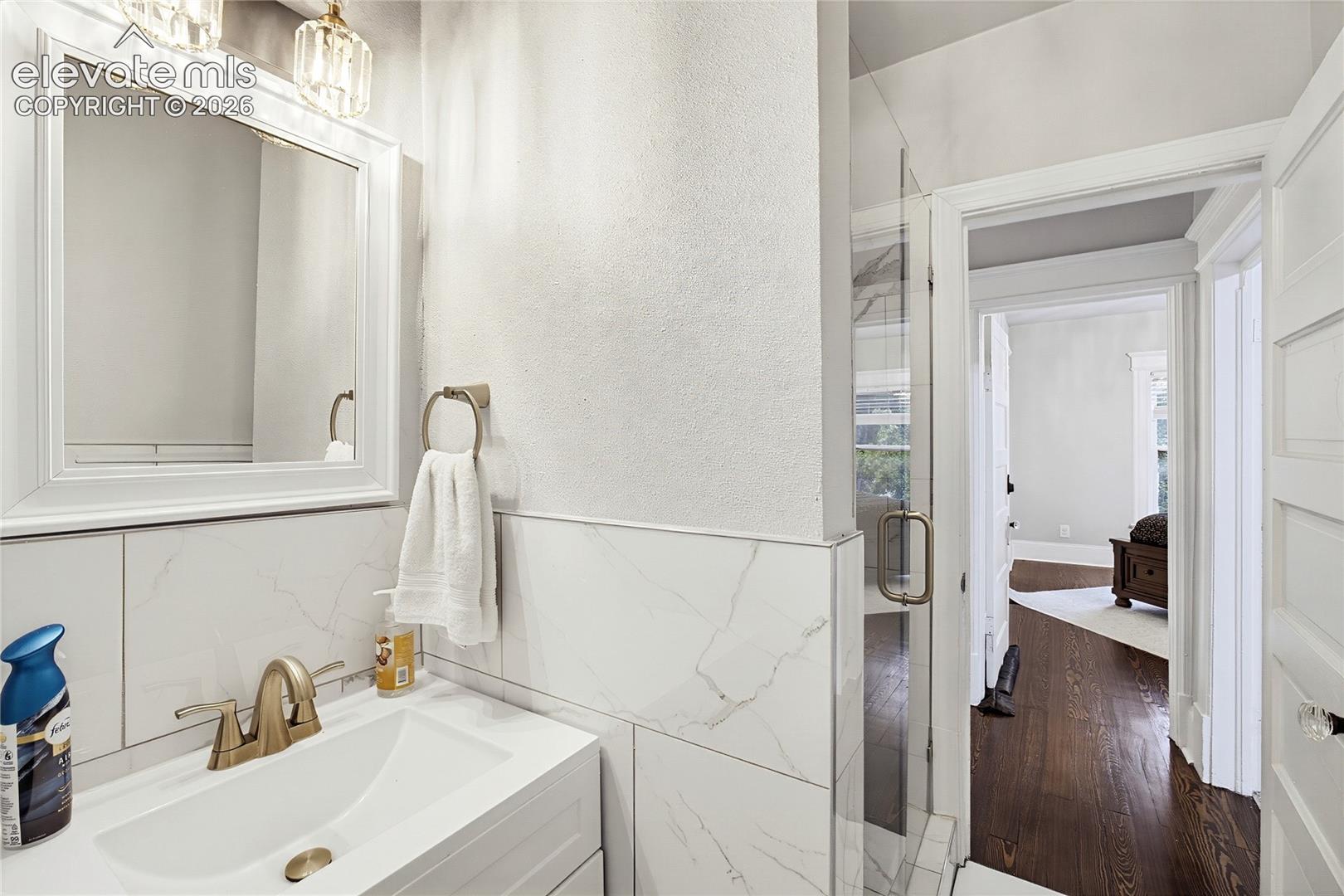 White vanity with an integrated rectangular sink, brass-finish faucet, framed mirror, and contemporary lighting