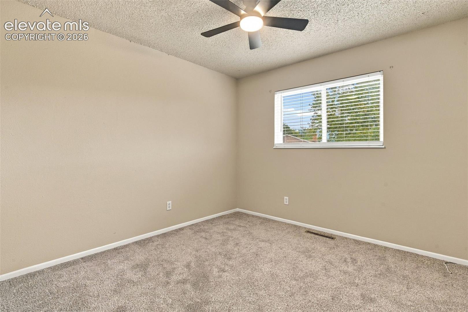 Neutral wall finishes, textured ceiling, installed ceiling fan with light fixture, carpeted flooring, and horizontal window blinds