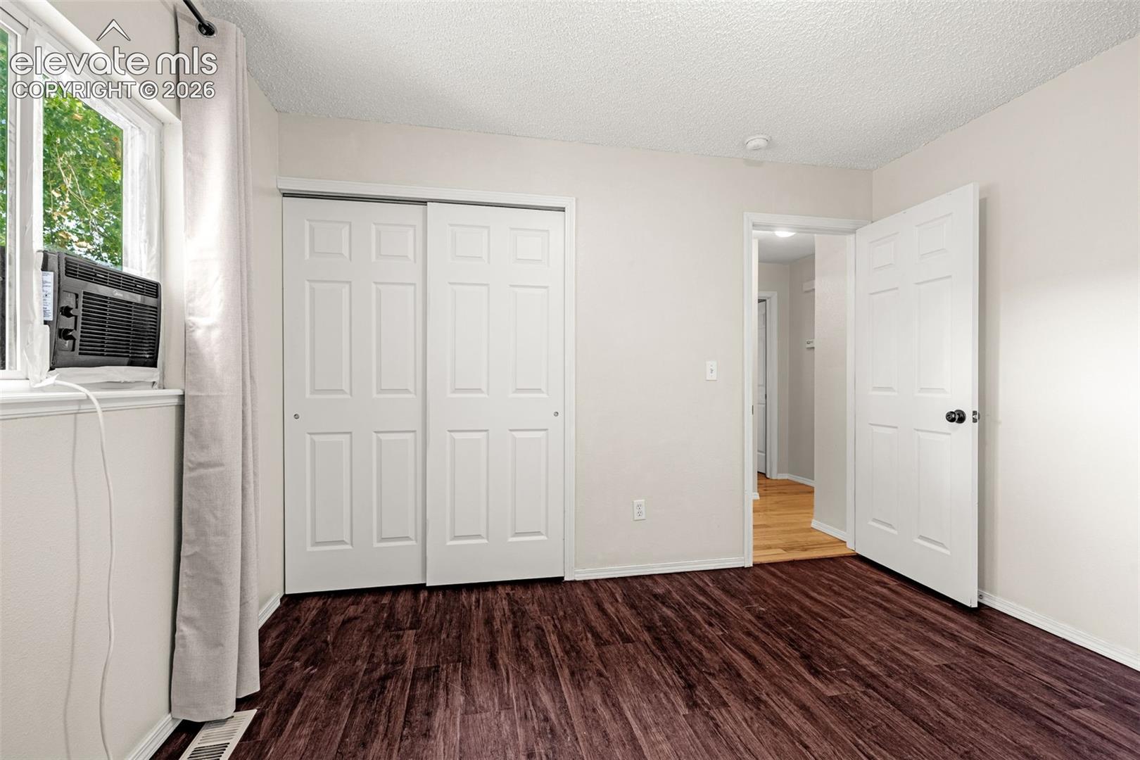 Bedroom featuring luxury vinyl flooring, light-colored walls, and a window with white trim