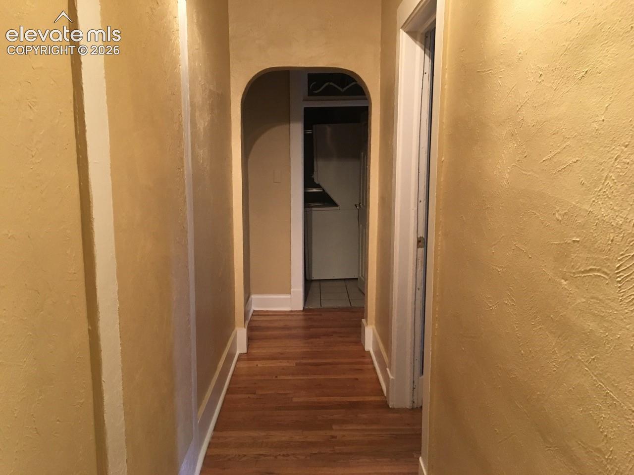 Archway entry with wood-finish flooring and textured walls