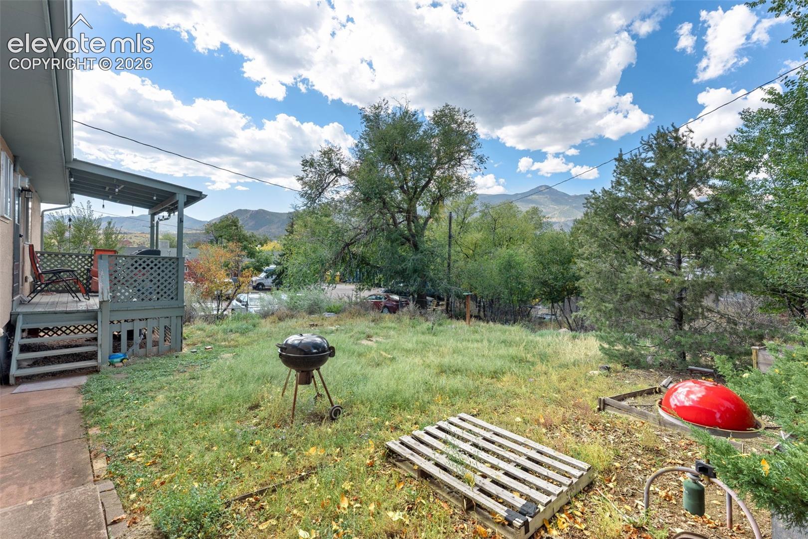Covered outdoor patio with lattice detailing, overlooking a spacious yard and distant mountain scenery