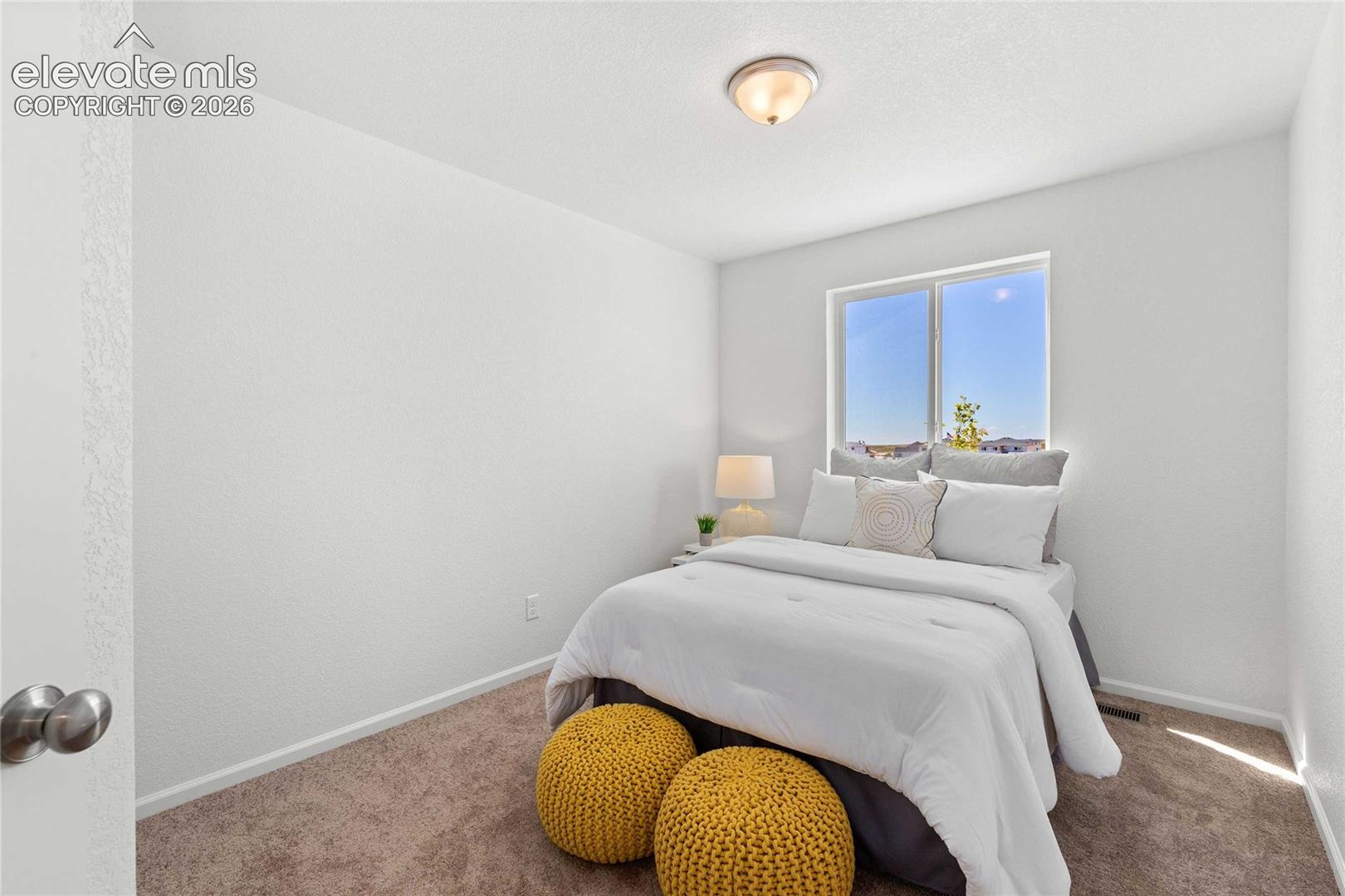 Bright secondary bedroom featuring large windows with natural light, neutral wall finishes, and wood-finish flooring throughout
*photos  of a model home*