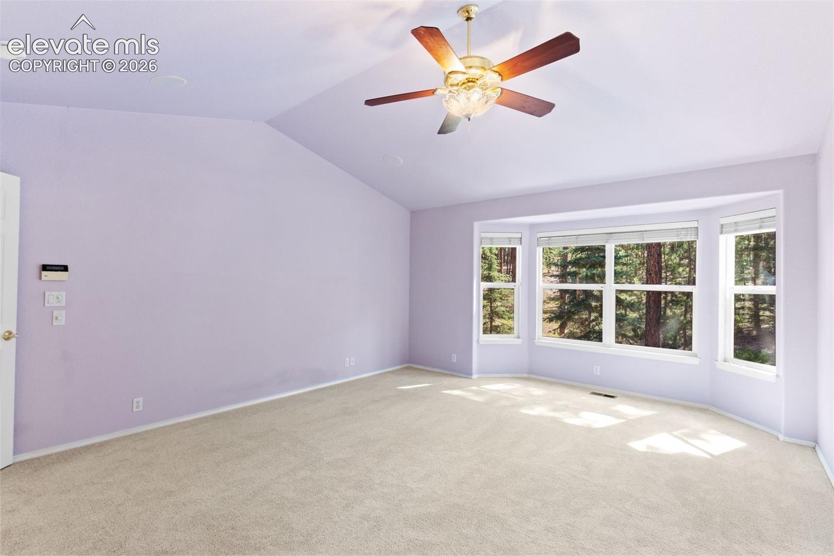Primary bedroom with vaulted ceiling, ceiling fan, ensuite bathroom, and walk in closet