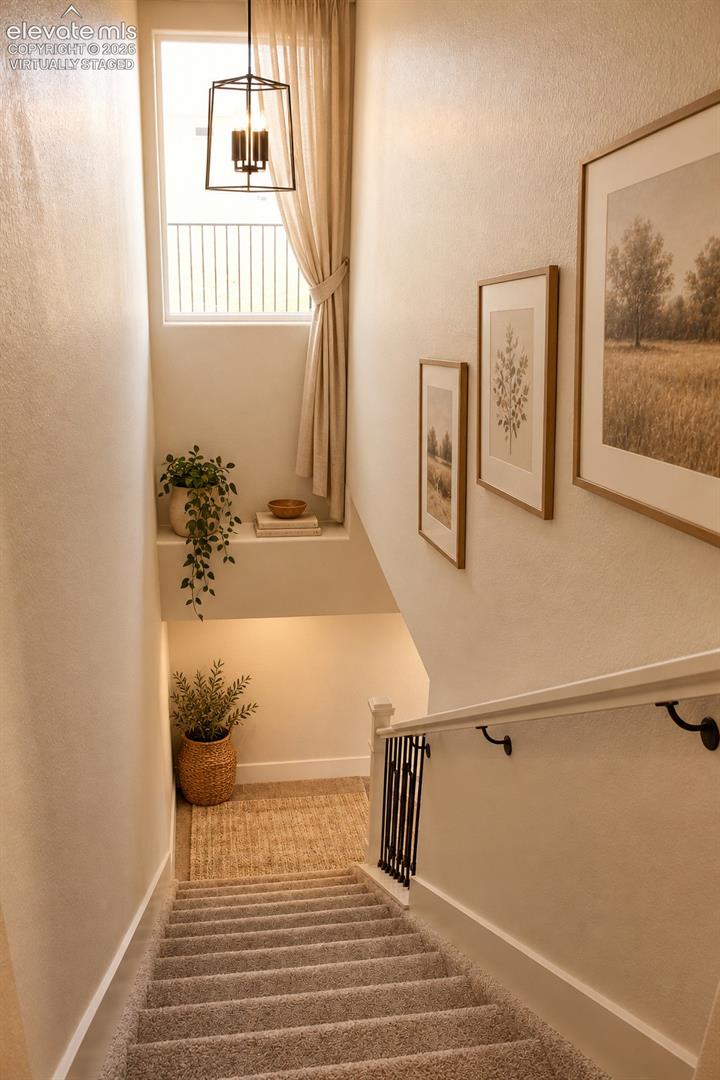 Virtually staged Carpeted staircase featuring a window with natural light, a metal and wood handrail, and a contemporary pendant light fixture